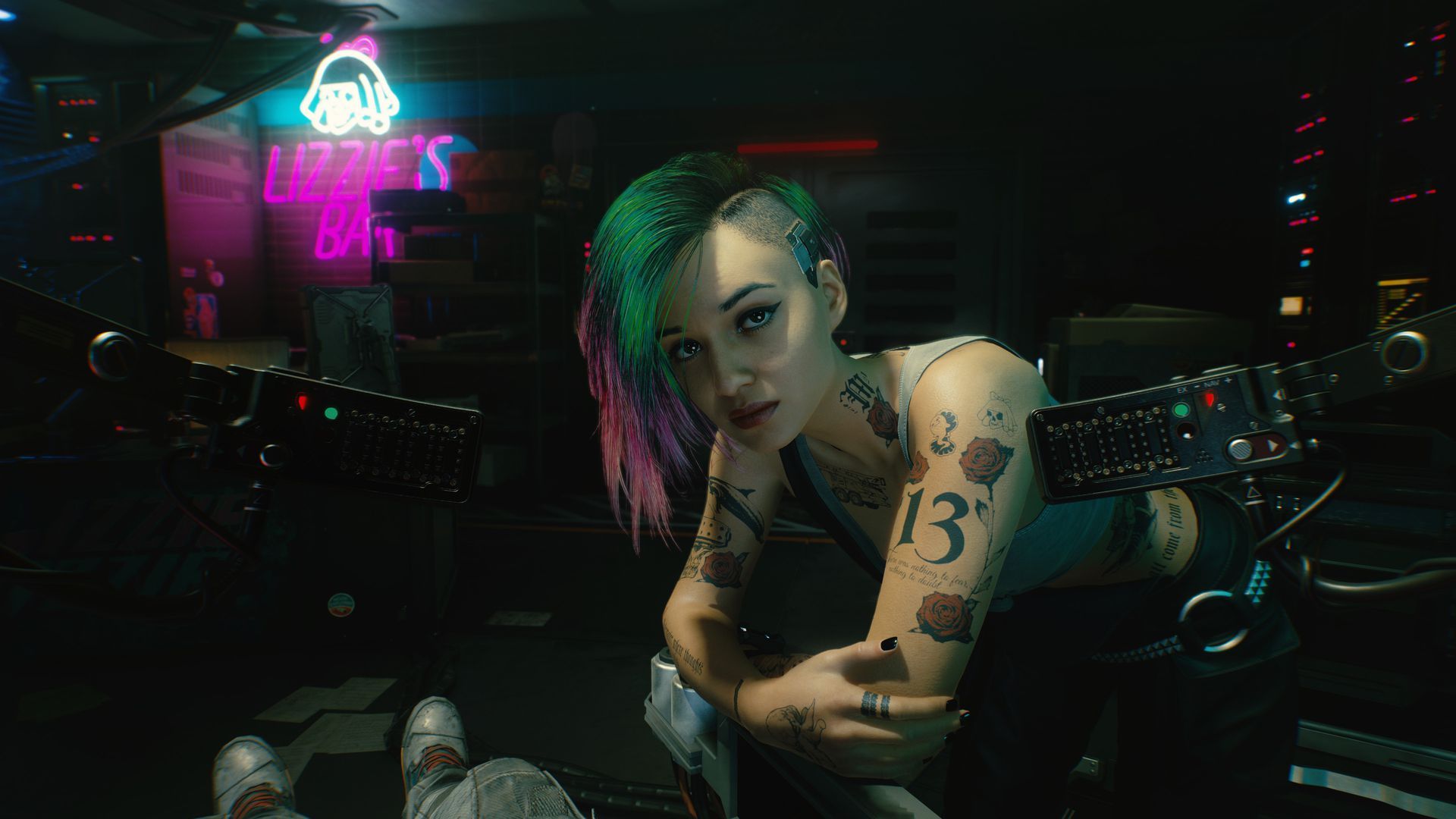 A screenshot from a video game scene with a tattooed woman with a partially shaved head poses in a dark room.