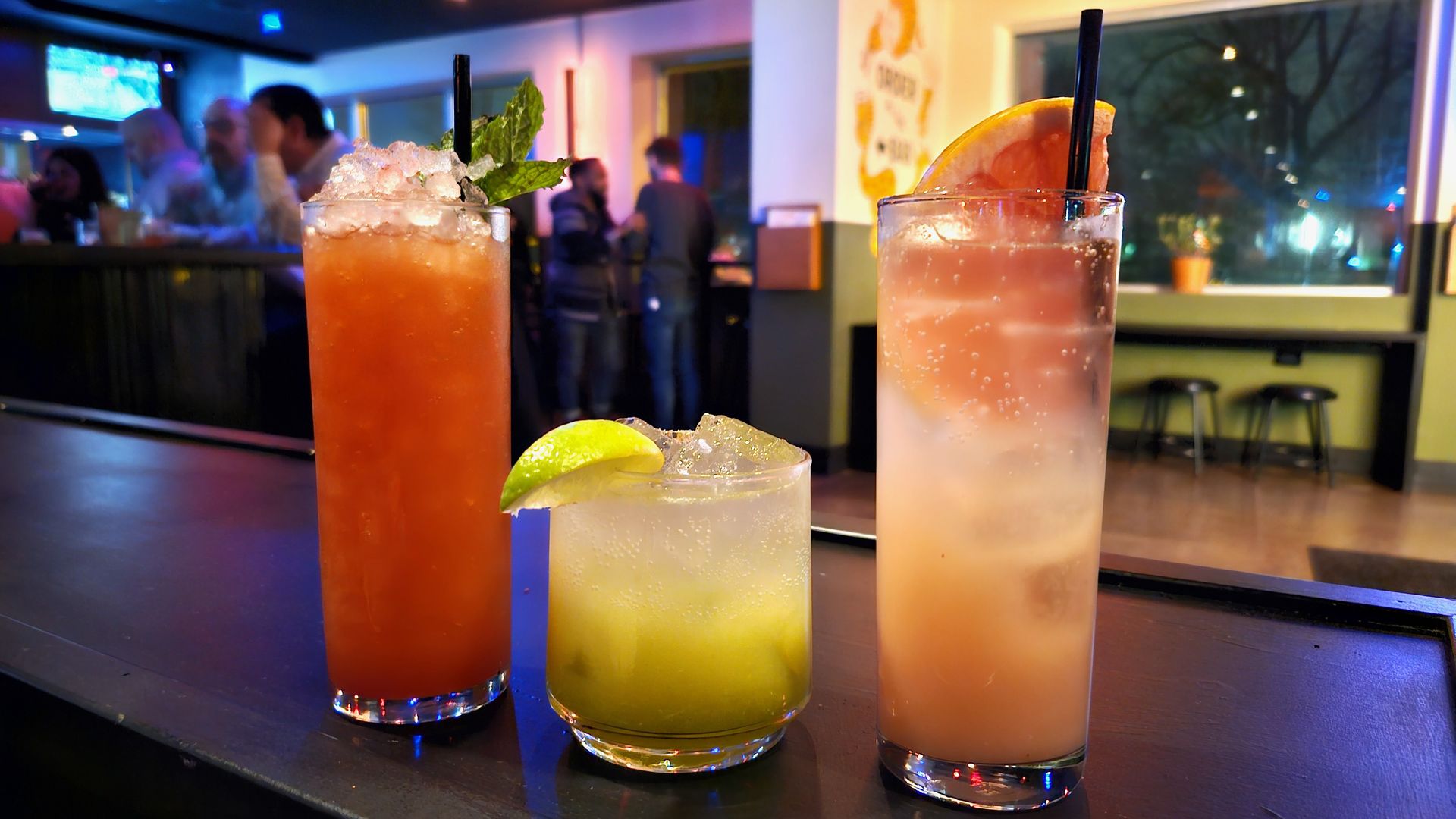 Three mocktail drinks lined on a counter, two pink and one green