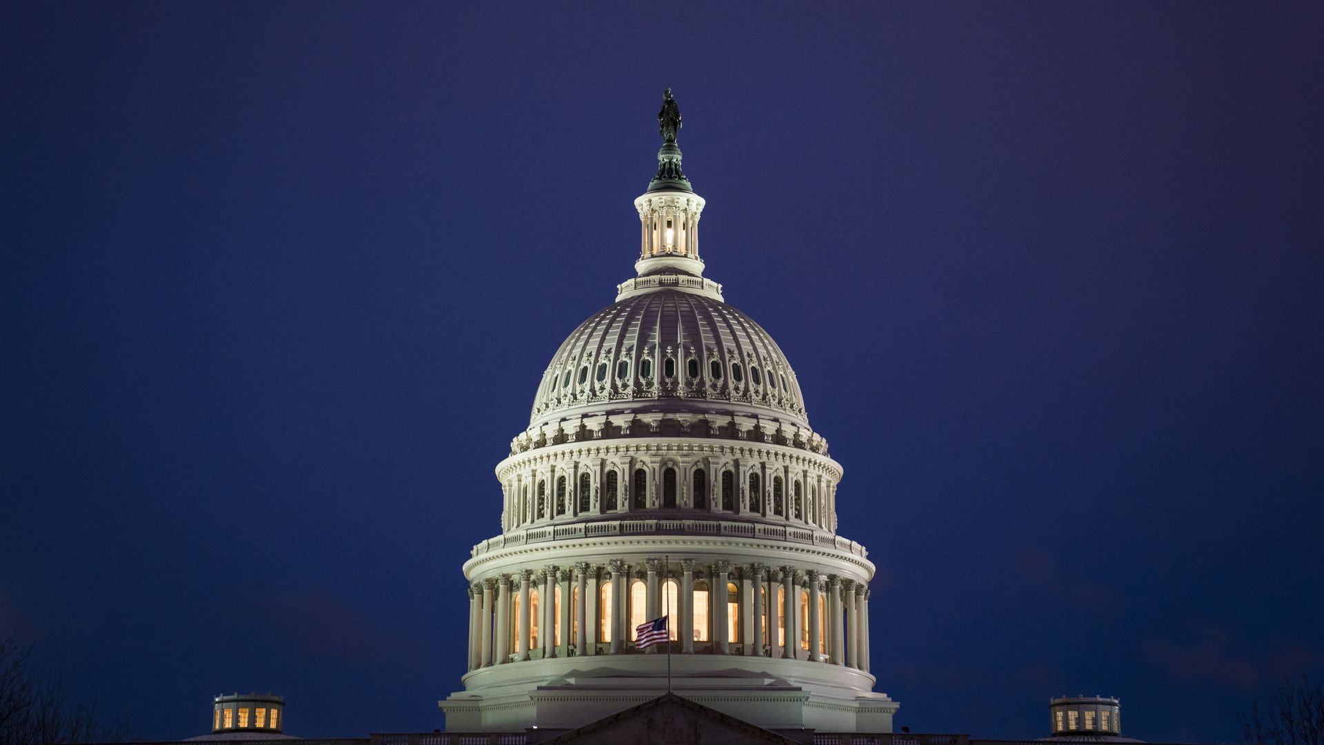 Capitol Dome lit up before blue sky.