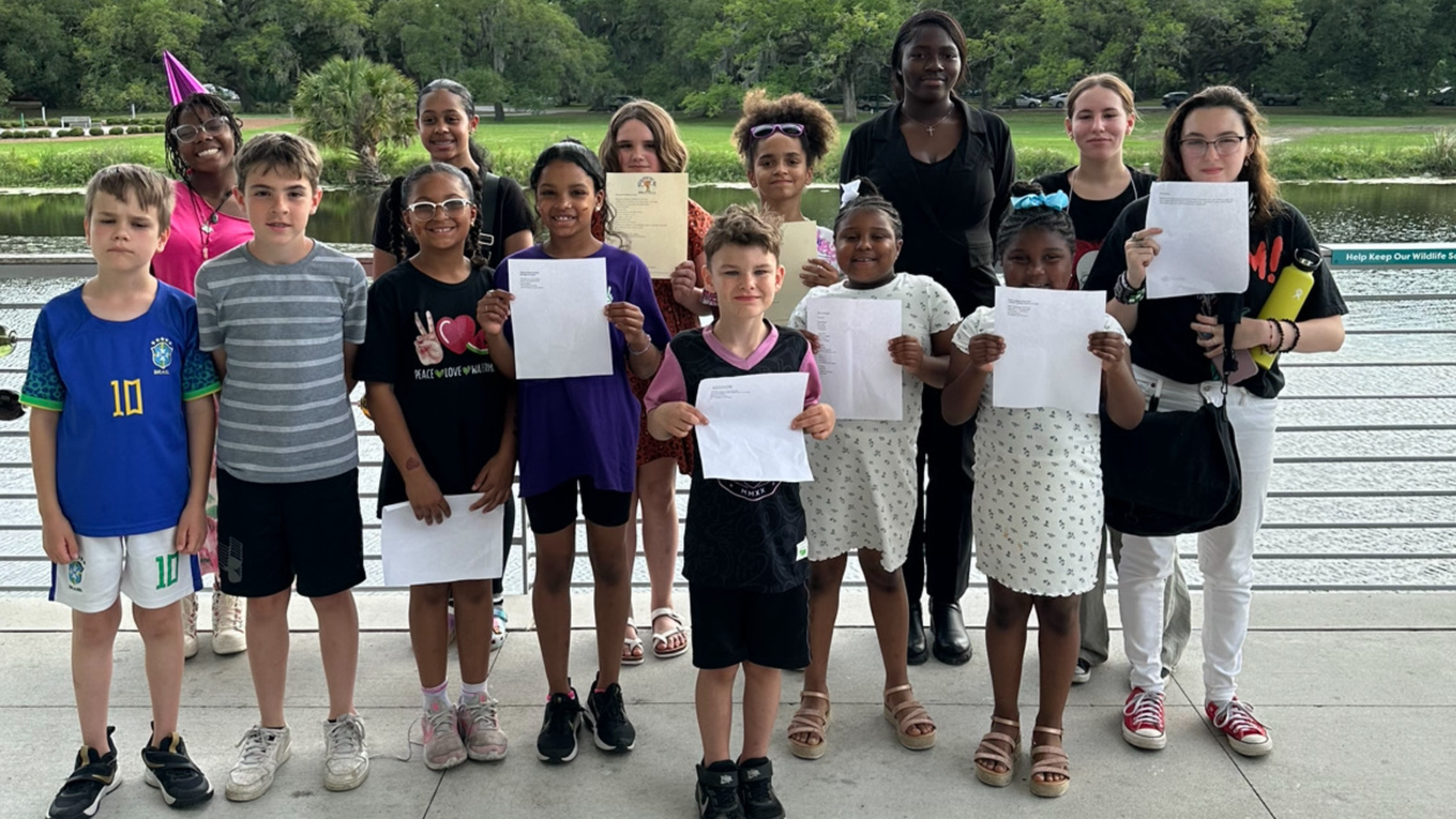 Photo shows a group of students standing together and holding poetry on papers.