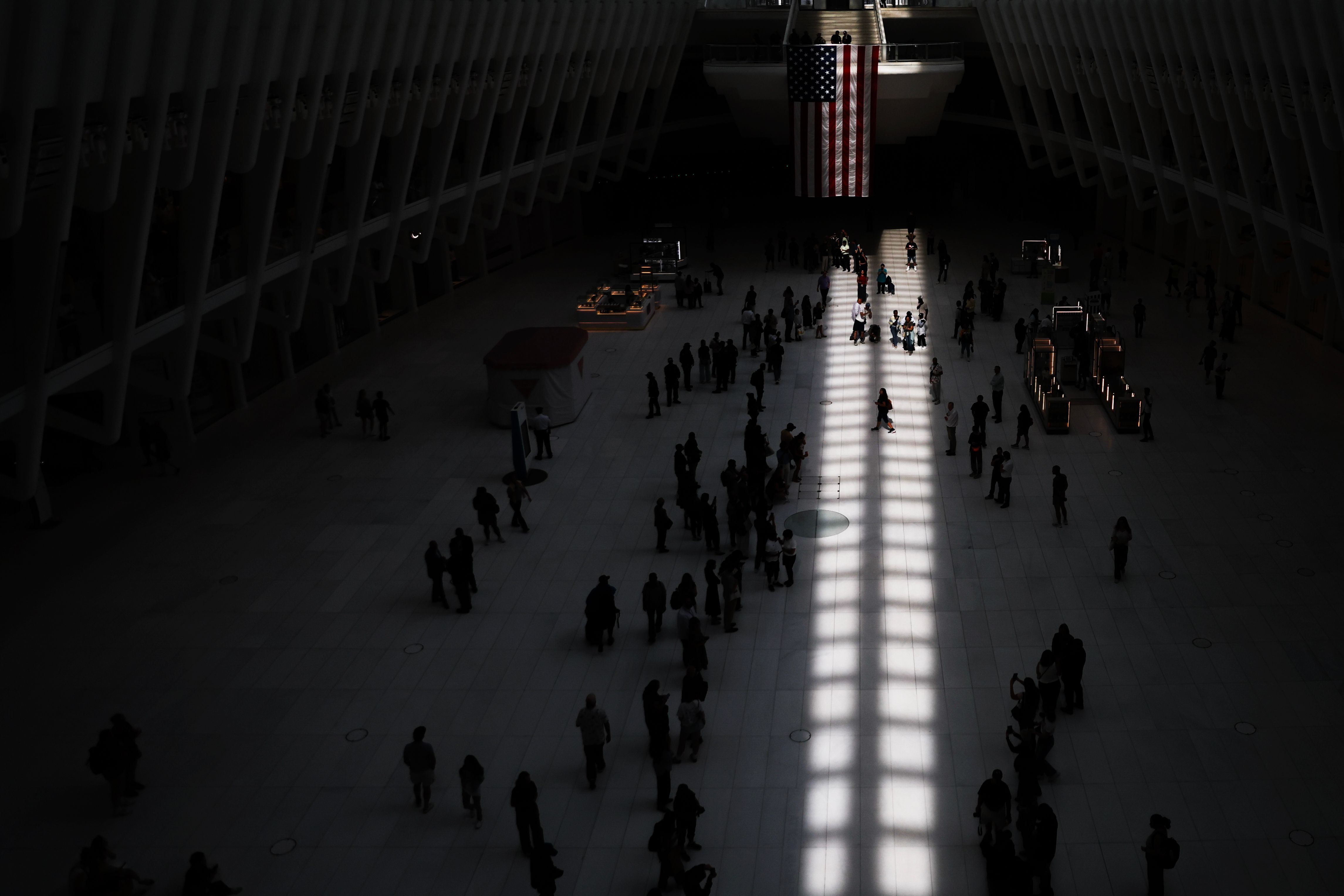 People make a path as two columns of light, representing the World Trade Center, appear on the floor appear on the floor inside the Oculus on the 25th anniversary of the Sept. 11, 2001, terrorist attacks, Friday, Sept. 11, 2026, in New York. (AP Photo/Heather Khalifa)