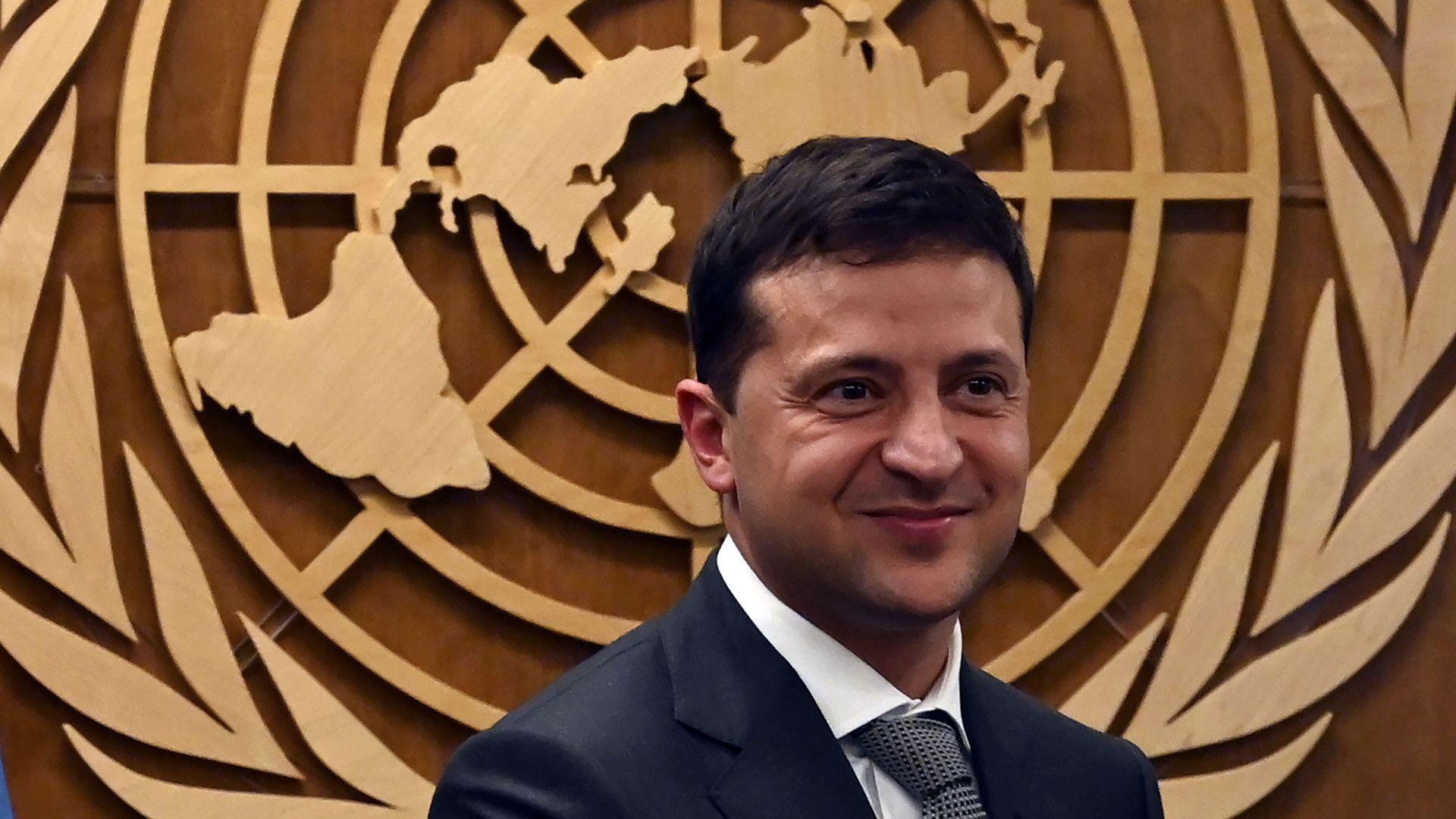 Zelensky in front of a wall-mounted UN logo