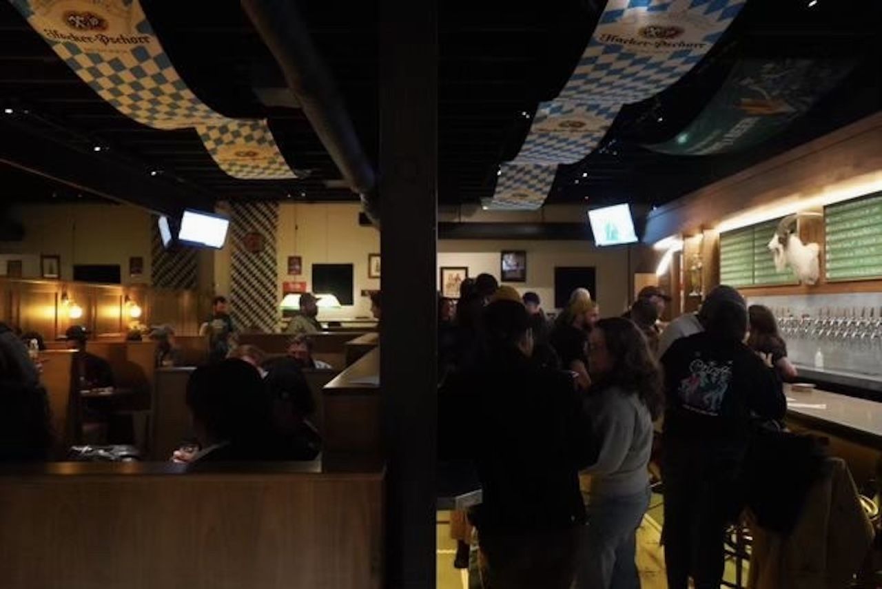 The inside of a dark bar with German banners along the roof.