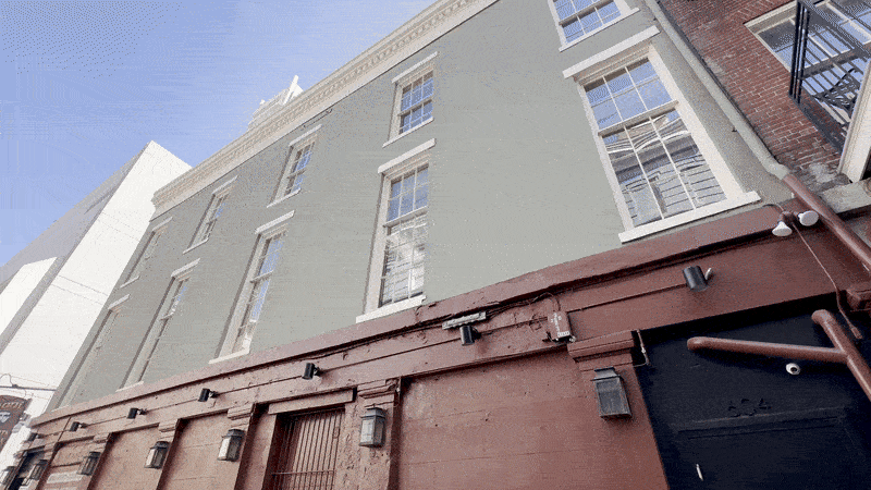 Image shows a building and a memorial plaque for the Up Stairs Lounge fire.