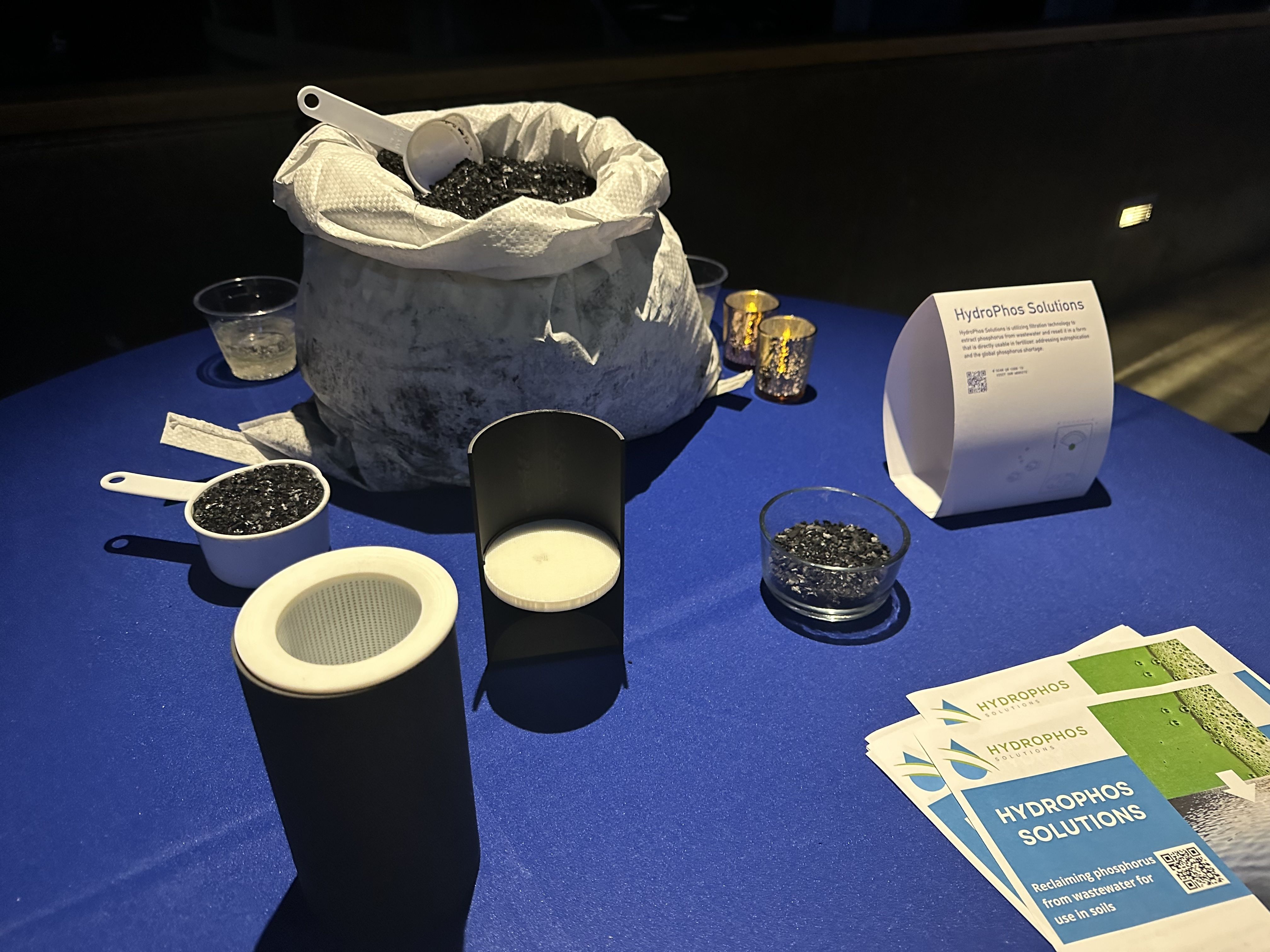 A pile of biochar and a miniature replica of a tank Hydrophos Solutions uses to trap phosphorus to clean waterways and sell it to farmers.