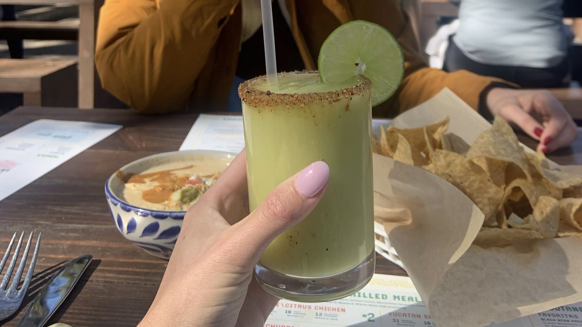 A margarita in the foreground. Food in the background.
