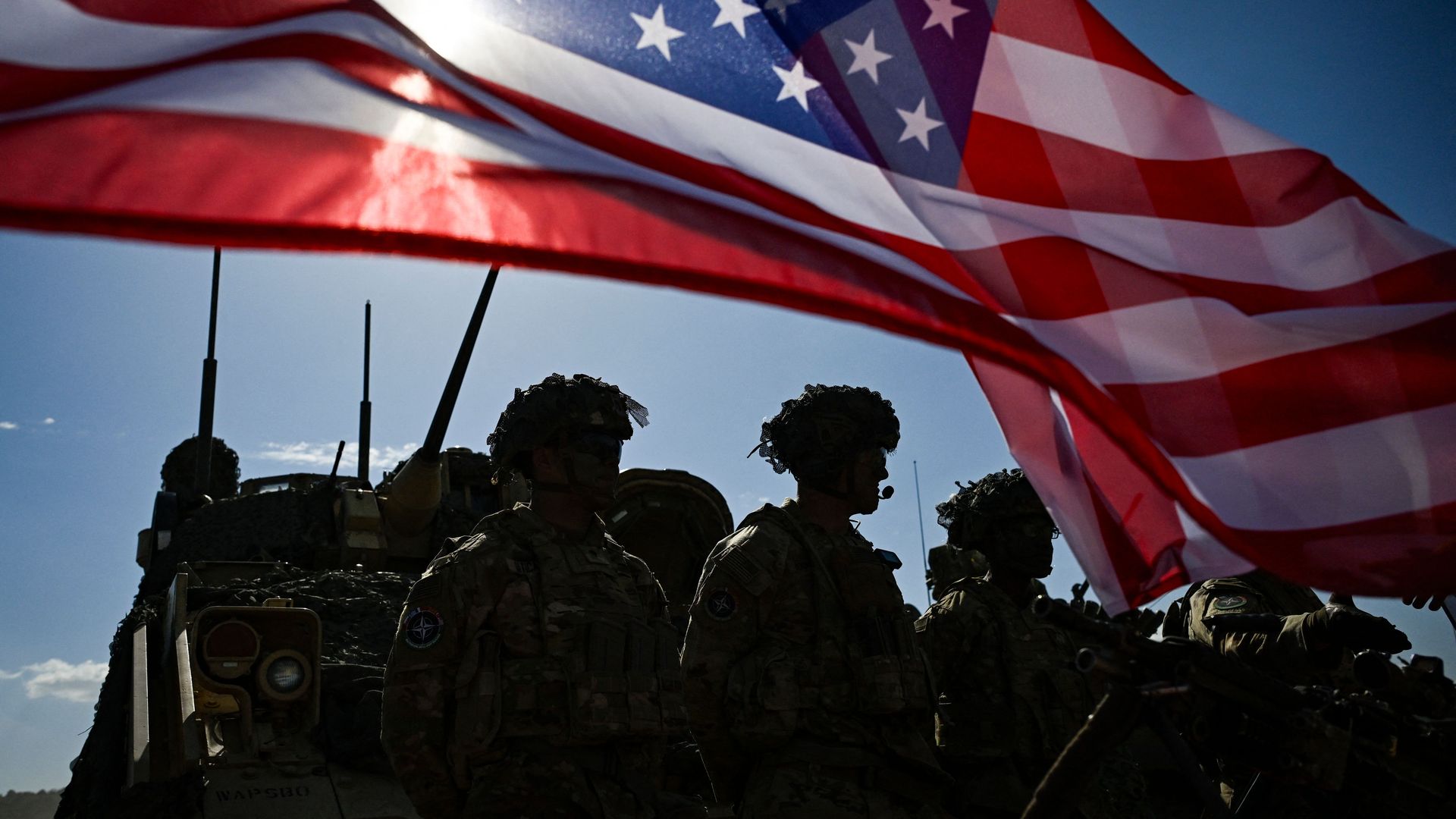 Soldiers below an American flag 