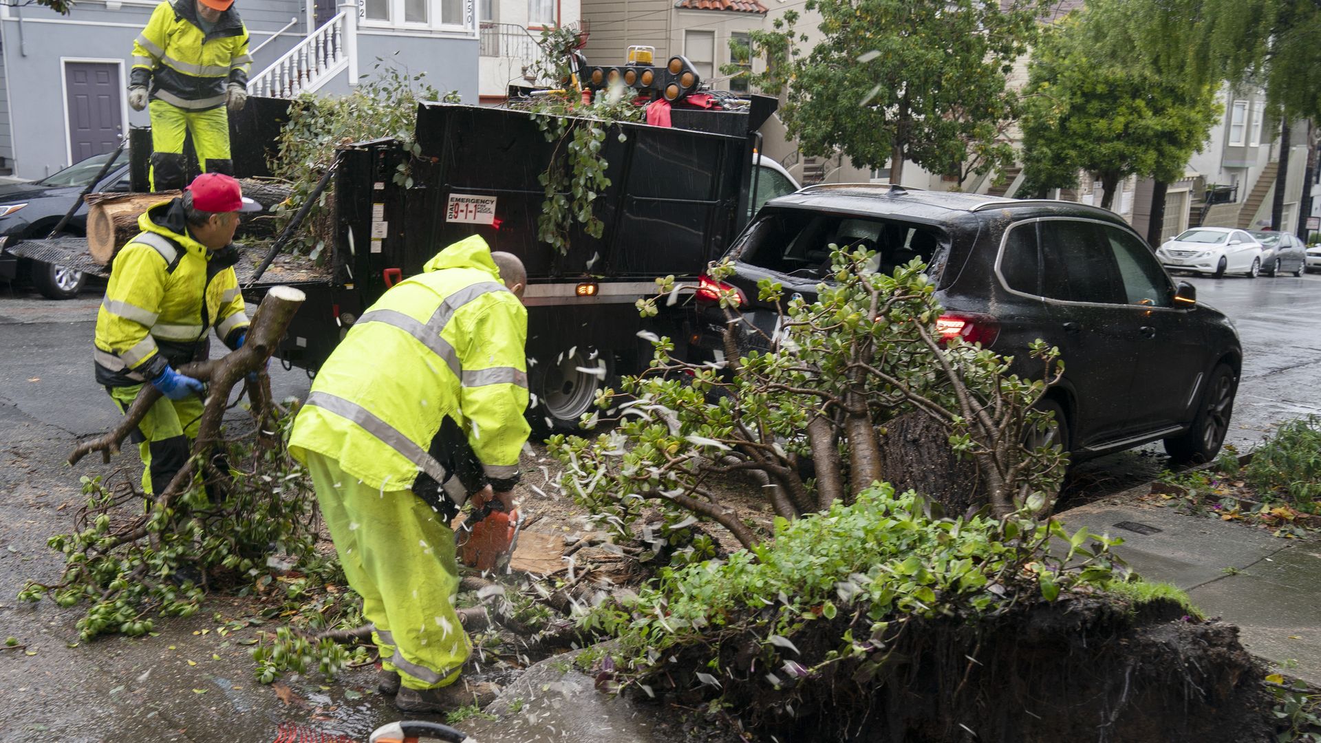 Photo of workers clearing up fallen trees from a street
