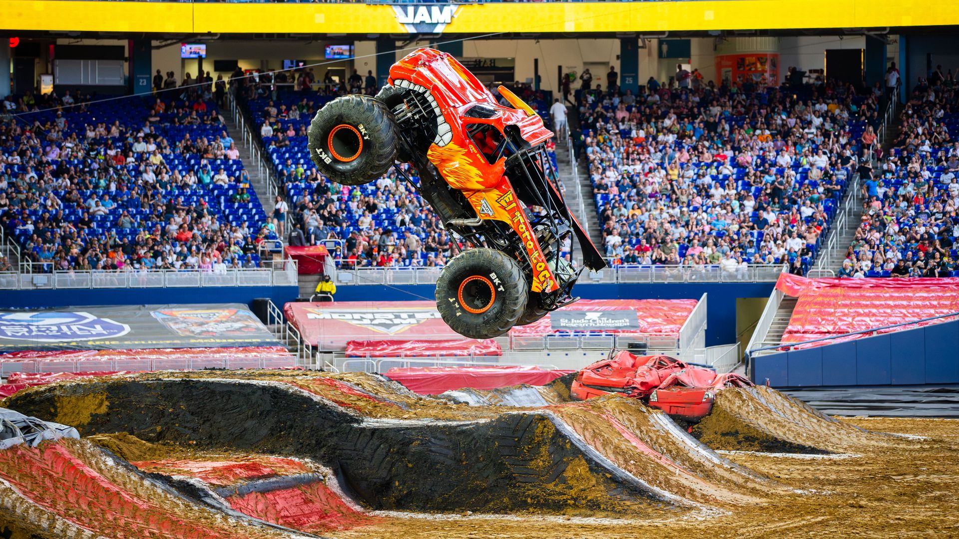 A photo of a red and orange truck in mid-air.