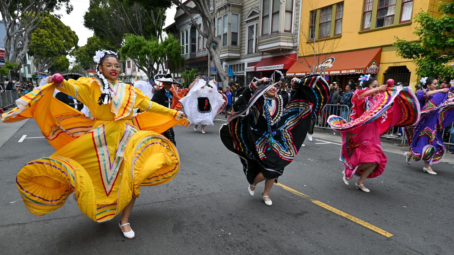 three people in colorful outfits dancing on the street