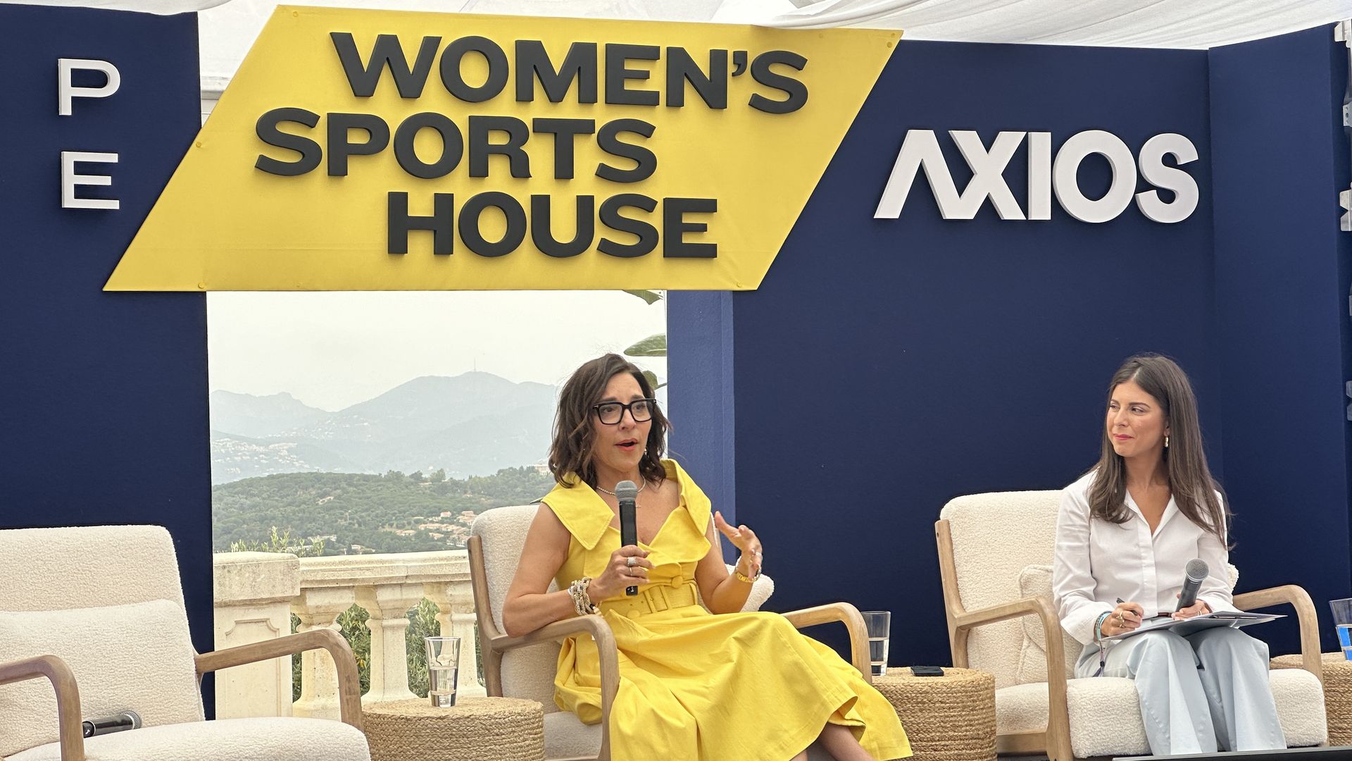 X CEO Linda Yaccarino and Axios' Sara Fischer sitting on a stage in front of a backdrop that says Women's Sports House and Axios