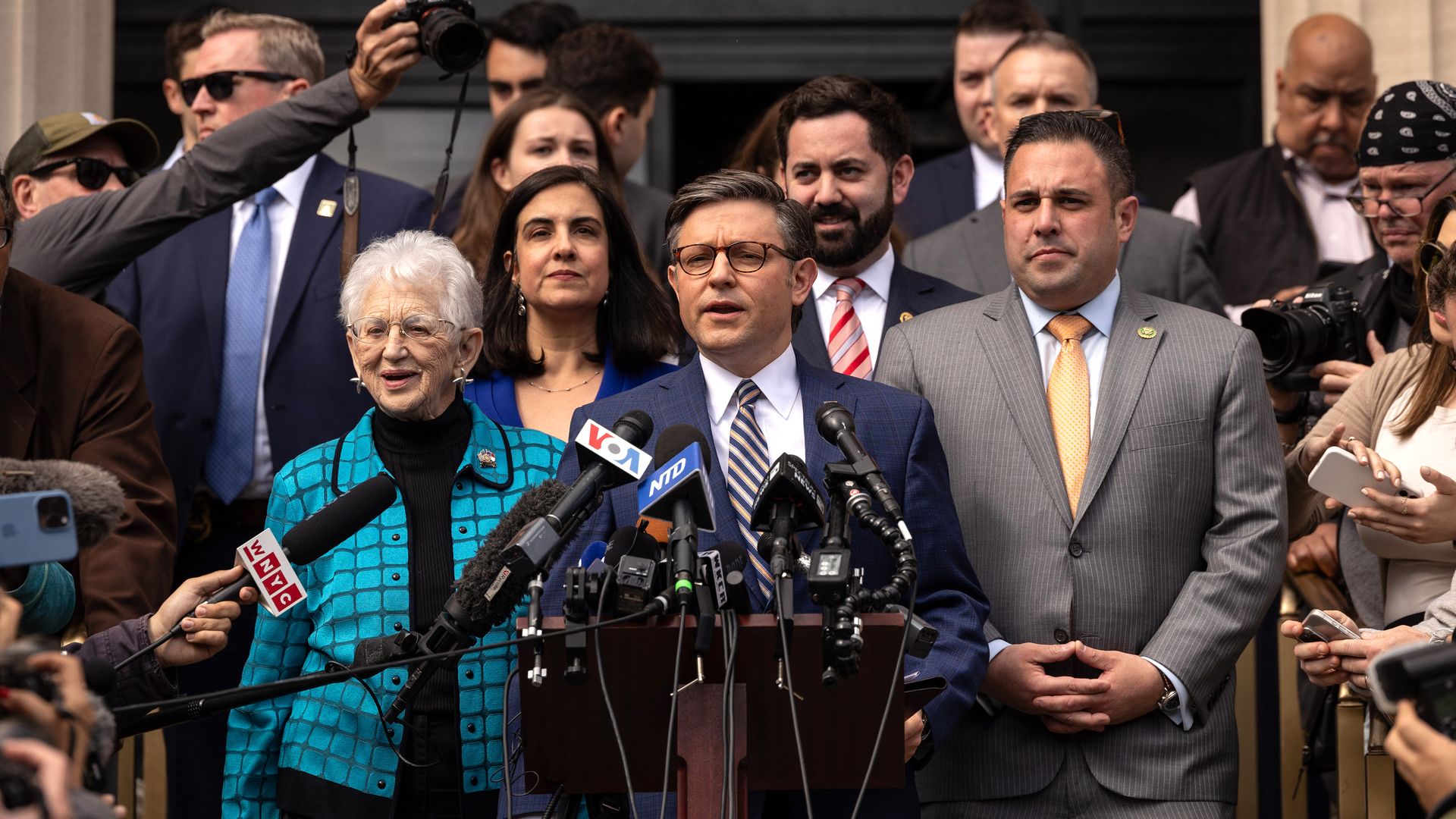 Rep. Mike Johnson, wearing a blue suit, surrounded by GOP colleagues and press on the steps of Columbia's Low Library.