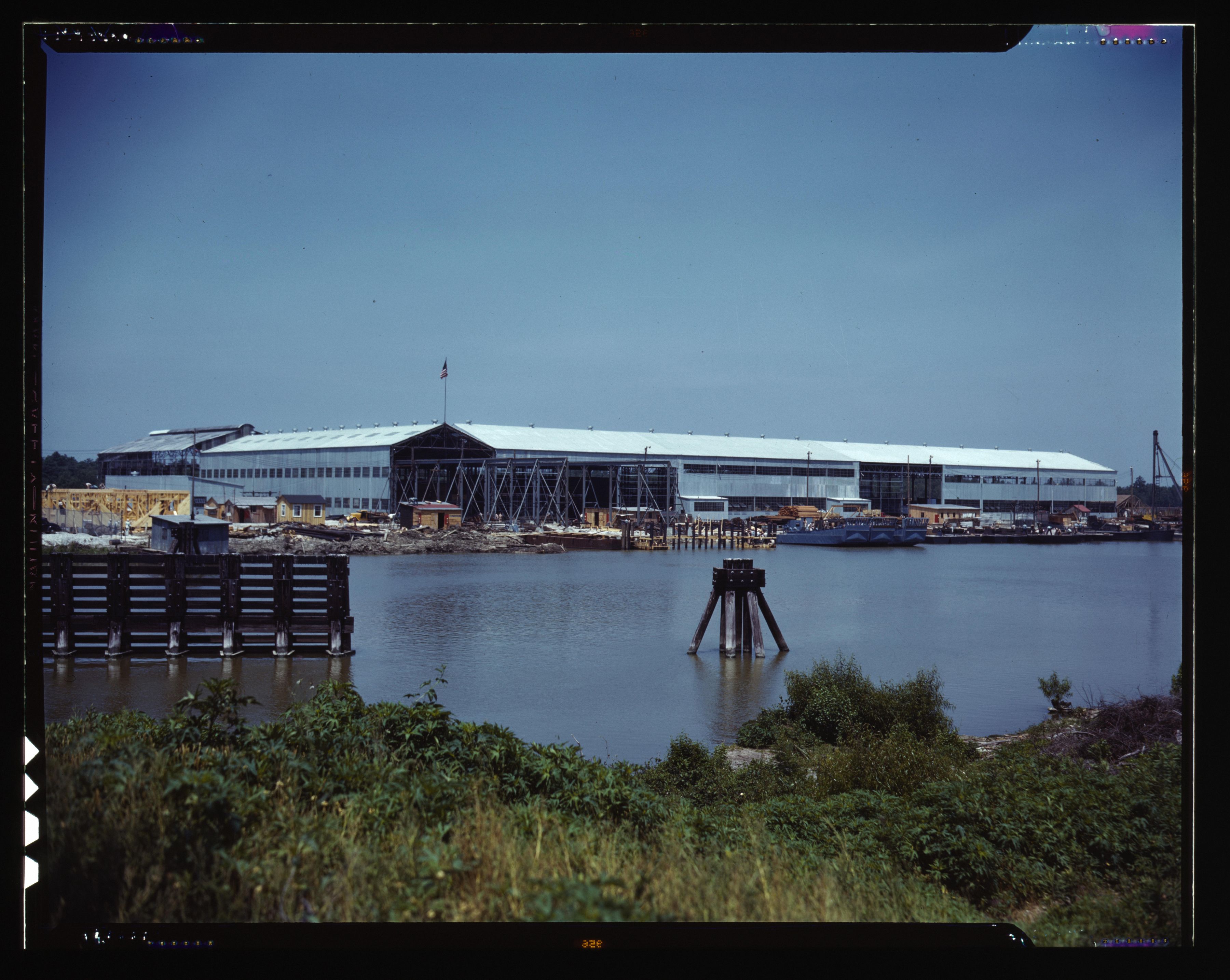 Photo shows a big metal warehouse on the water.