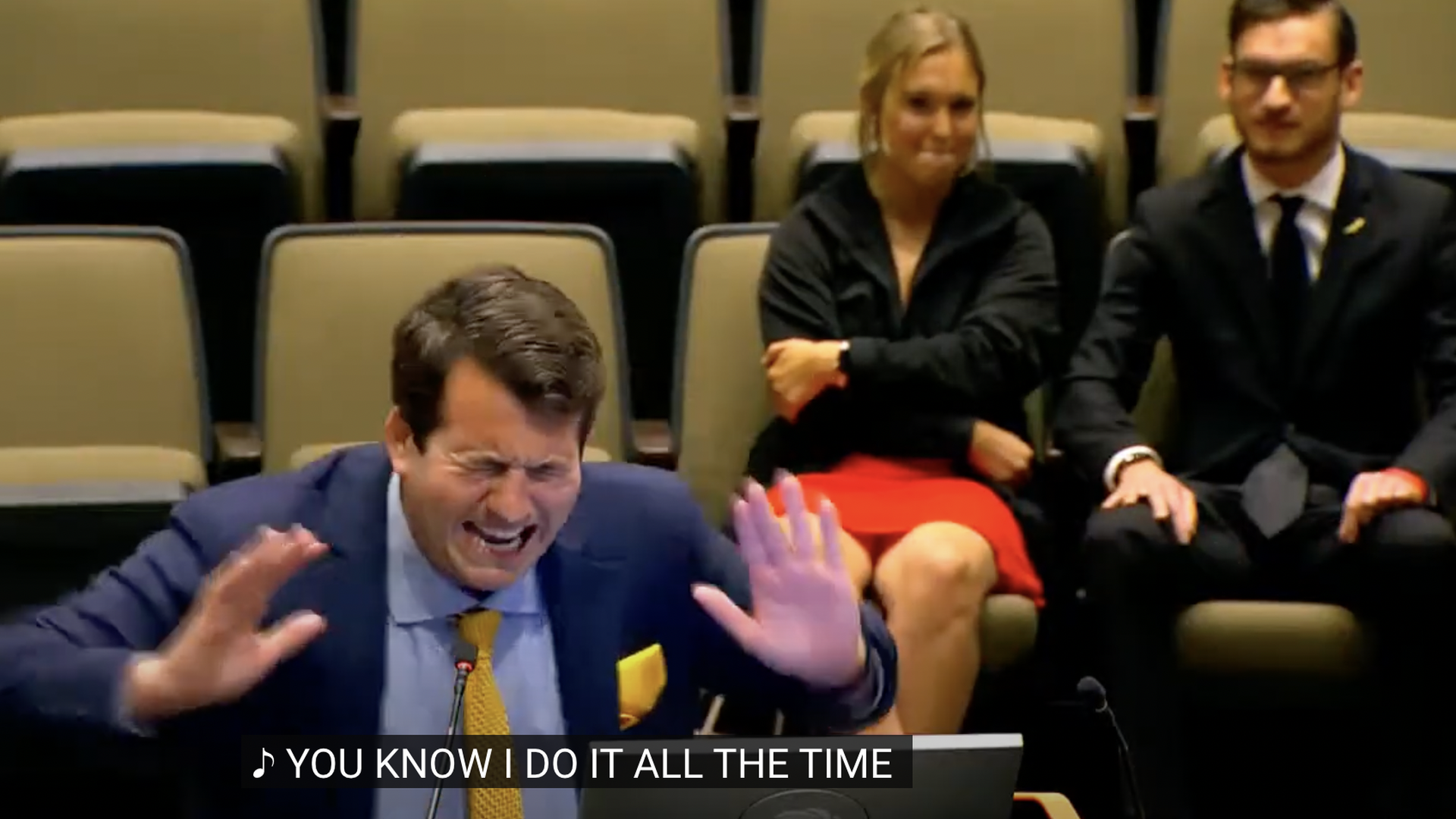 A man in a suit rapping terribly