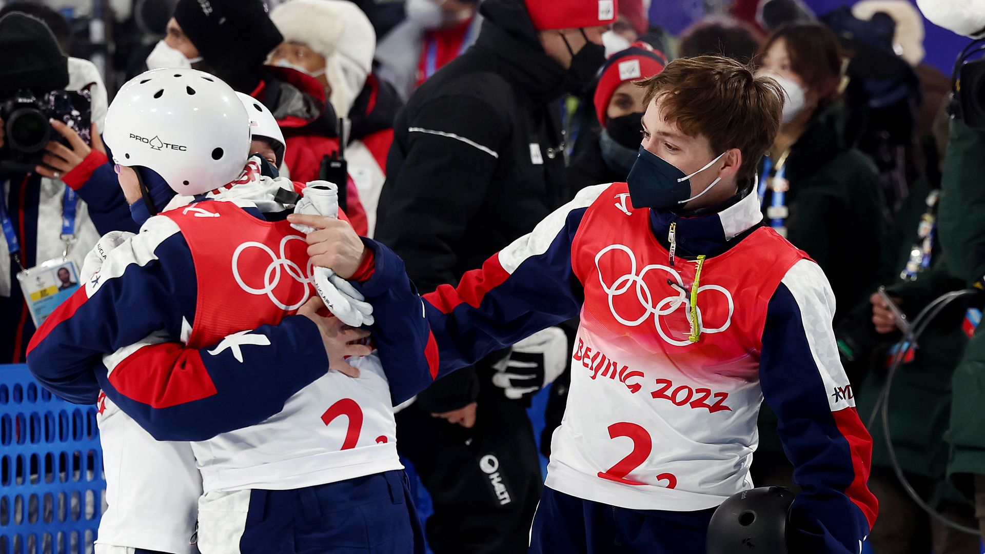Justin Schoenefeld (C), Ashley Caldwell (L) and Christopher Lillis (R) embracing after winning a gold medal in mixed team aerials in Beijing on Feb. 10.