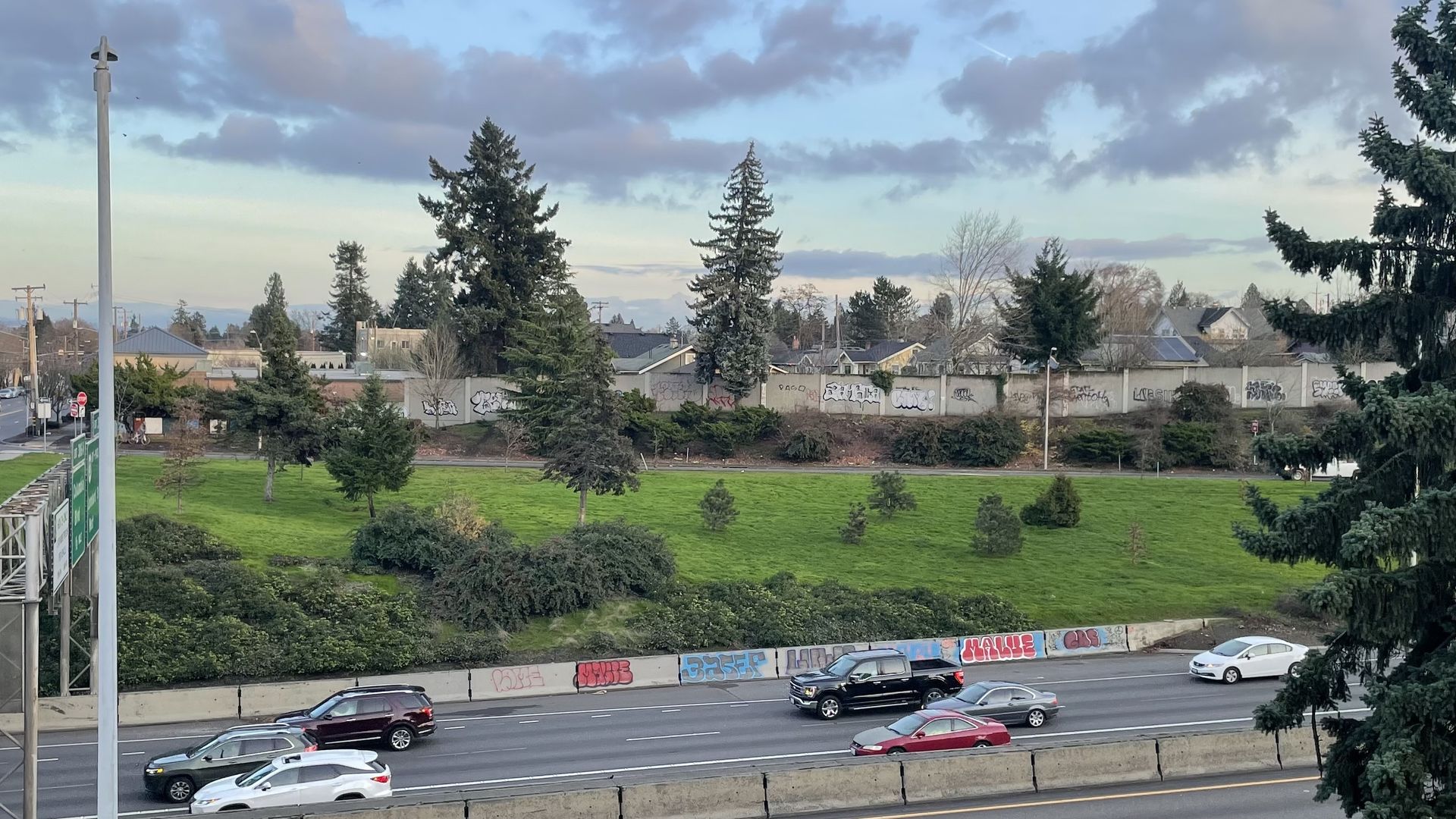 A photo of a highway with cars driving and graffiti along the median.