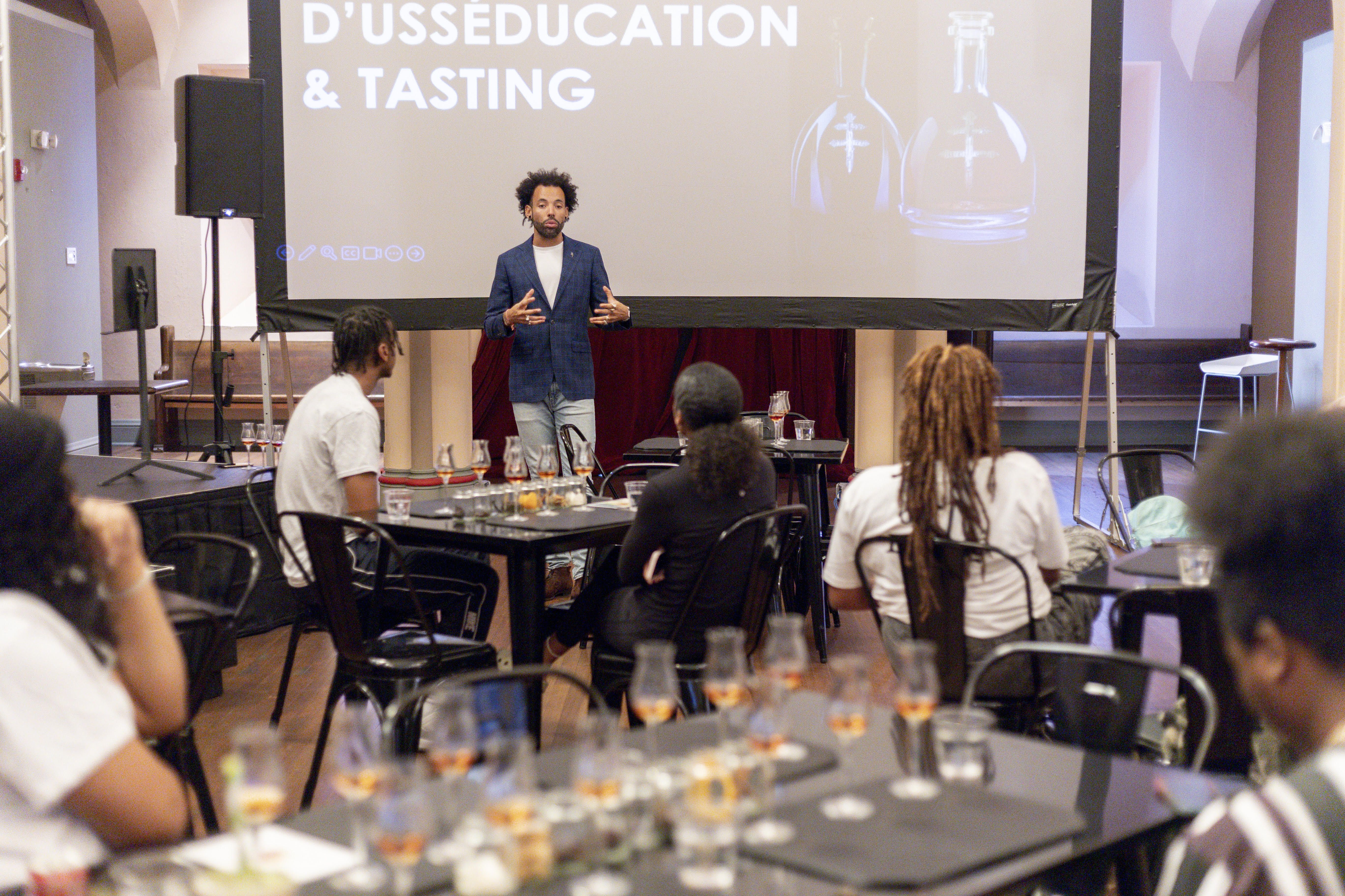 A seminar-style class with a slideshow saying "D'usse education and tasting."