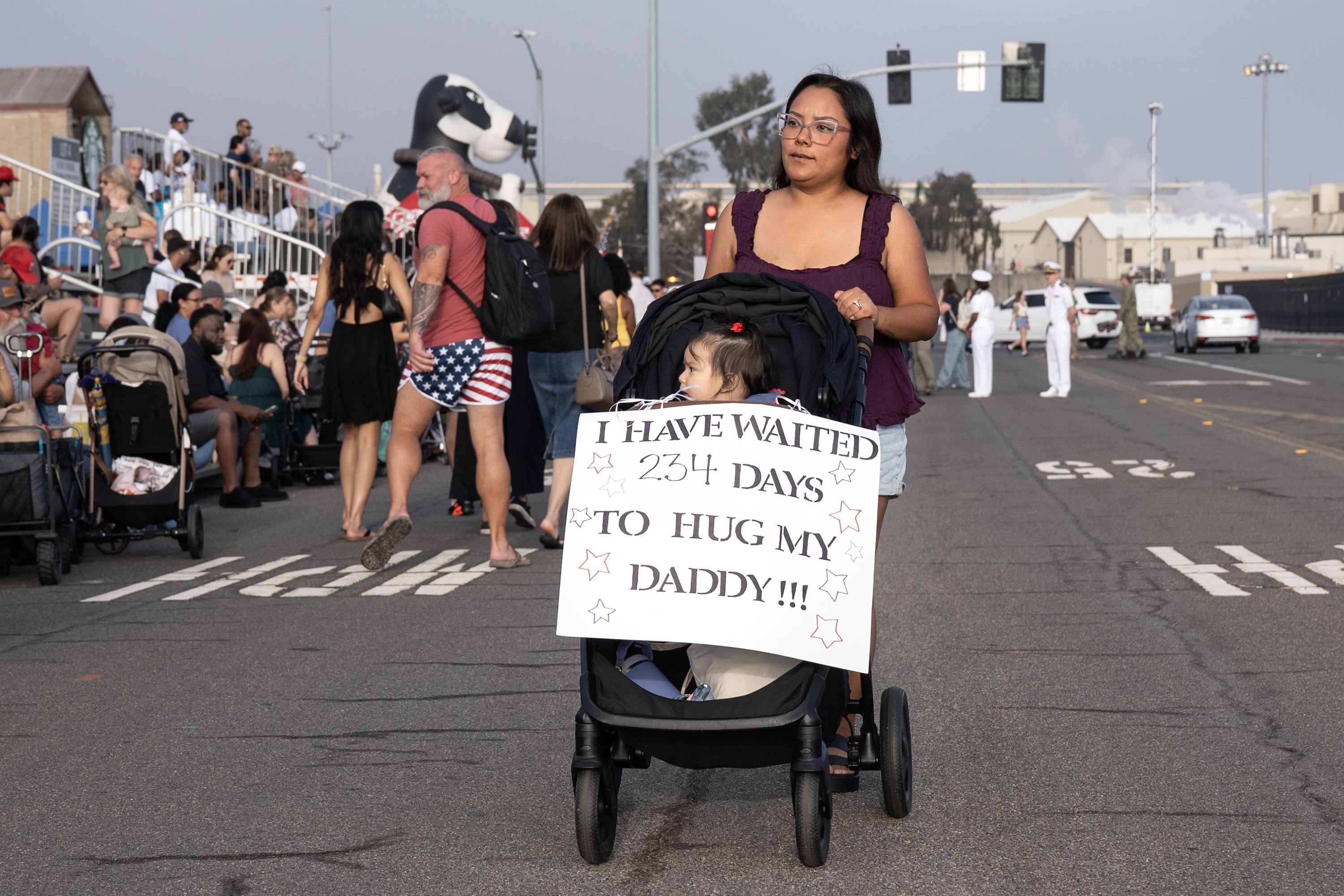 Coronado, CA - Brenda Rivas pushes her seven month old daughter Evie Rivas in a stroller as they find their seats on the bleachers before the USS Abraham Lincoln returns to port at Naval Air Station North Island after 322 days of deployment on Thursday, Oct. 8, 2026, in Coronado, CA. Evie Rivas has 