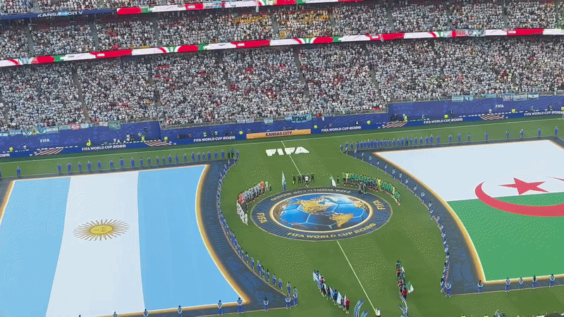 GIF showing a zoom in and zoom out of the opening ceremony of the first KC World Cup game including both Argentina and Algeria flags and teams on the pitch.