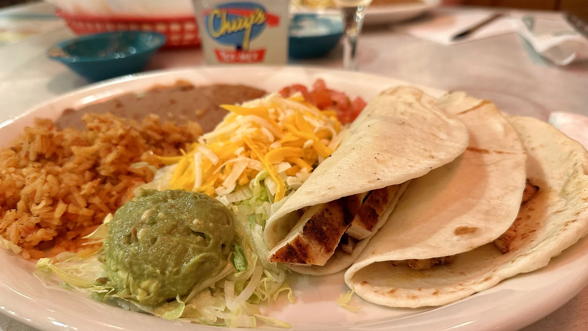 three tacos, guacamole, cheese, beans and rice