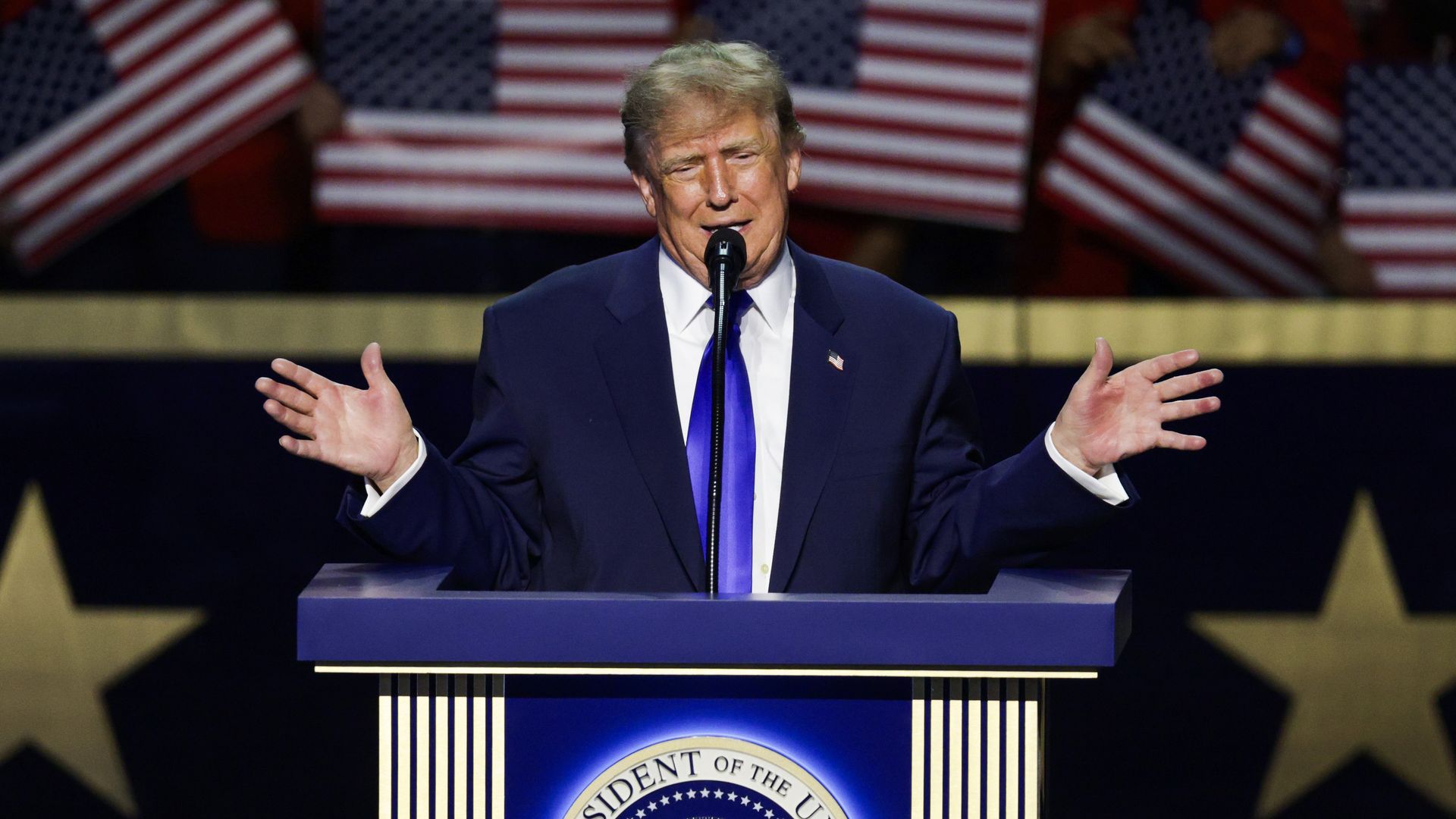 Trump gestures while speaking at a podium with his hands extended out