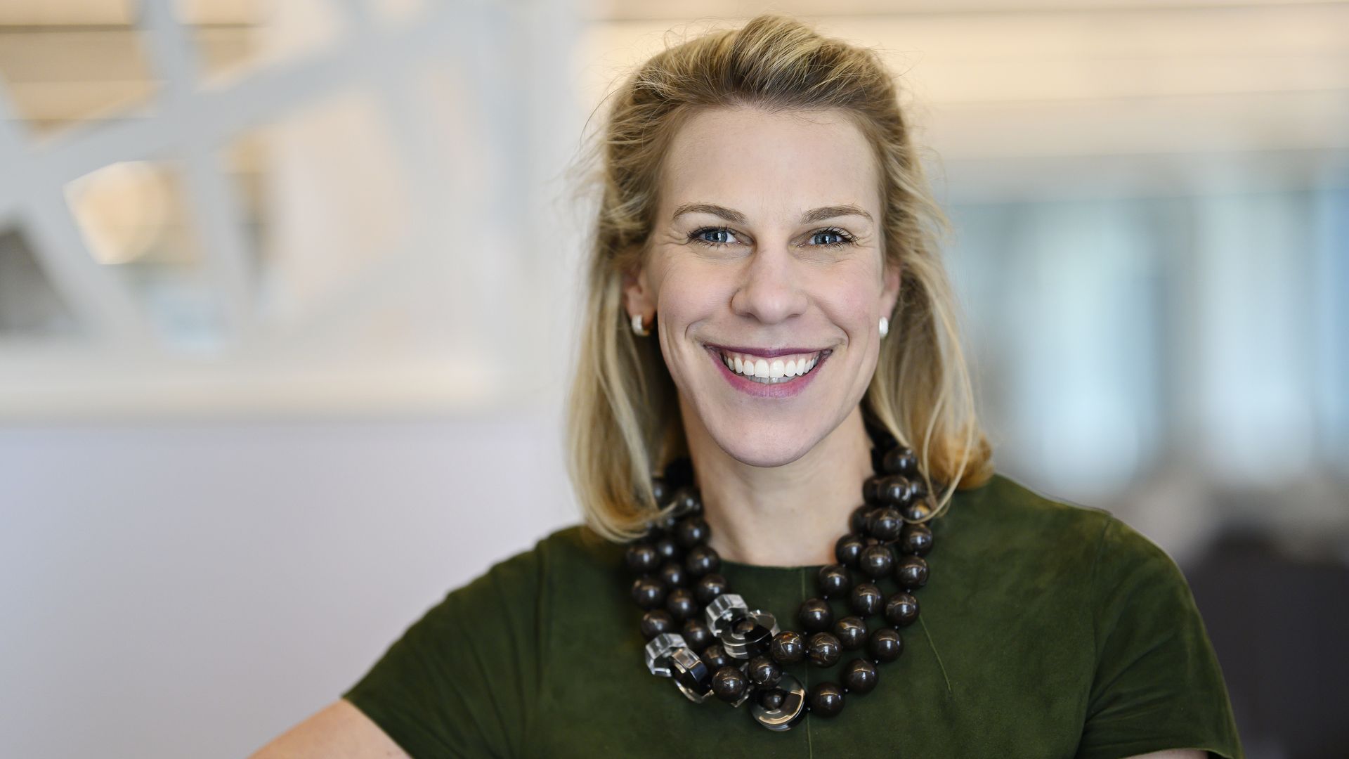 MassChallenge CEO poses for a picture, wearing a green dress and large necklace.