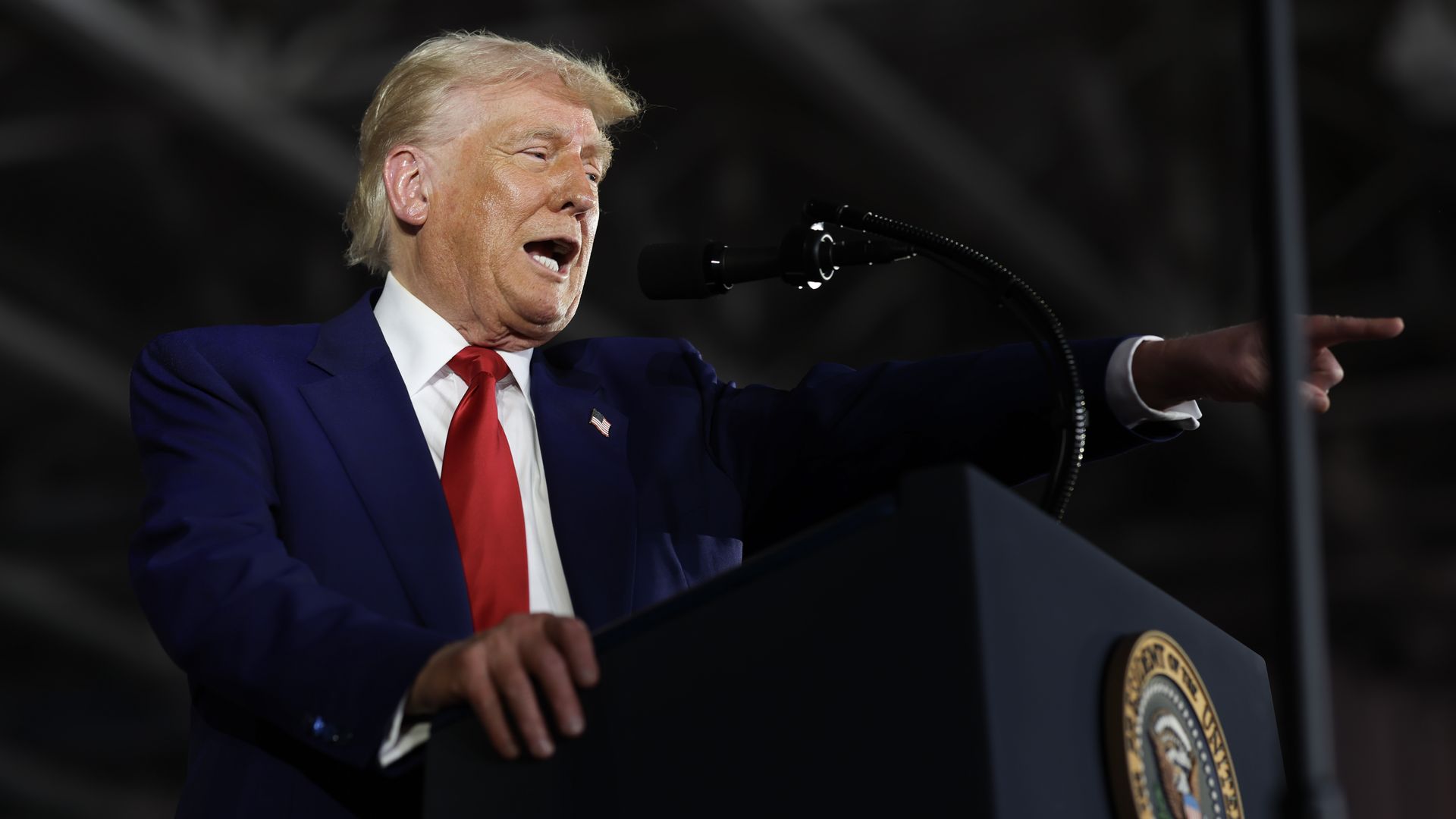 Trump points to the crowd from behind a lectern during a speech.