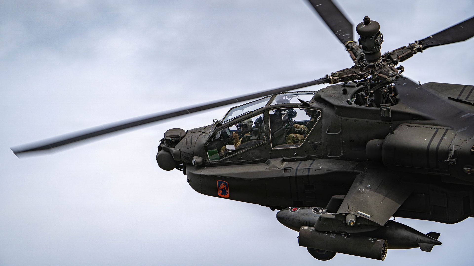 Close-up of a military helicopter in flight, main rotor spinning.