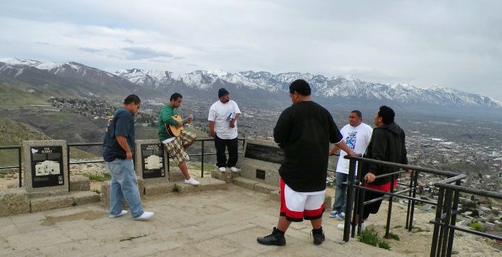 A group of men sing along with a guitar on a mountain overlook