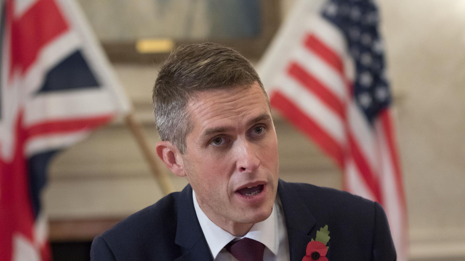 Gavin Williamson in front of U.S. and U.K. flags