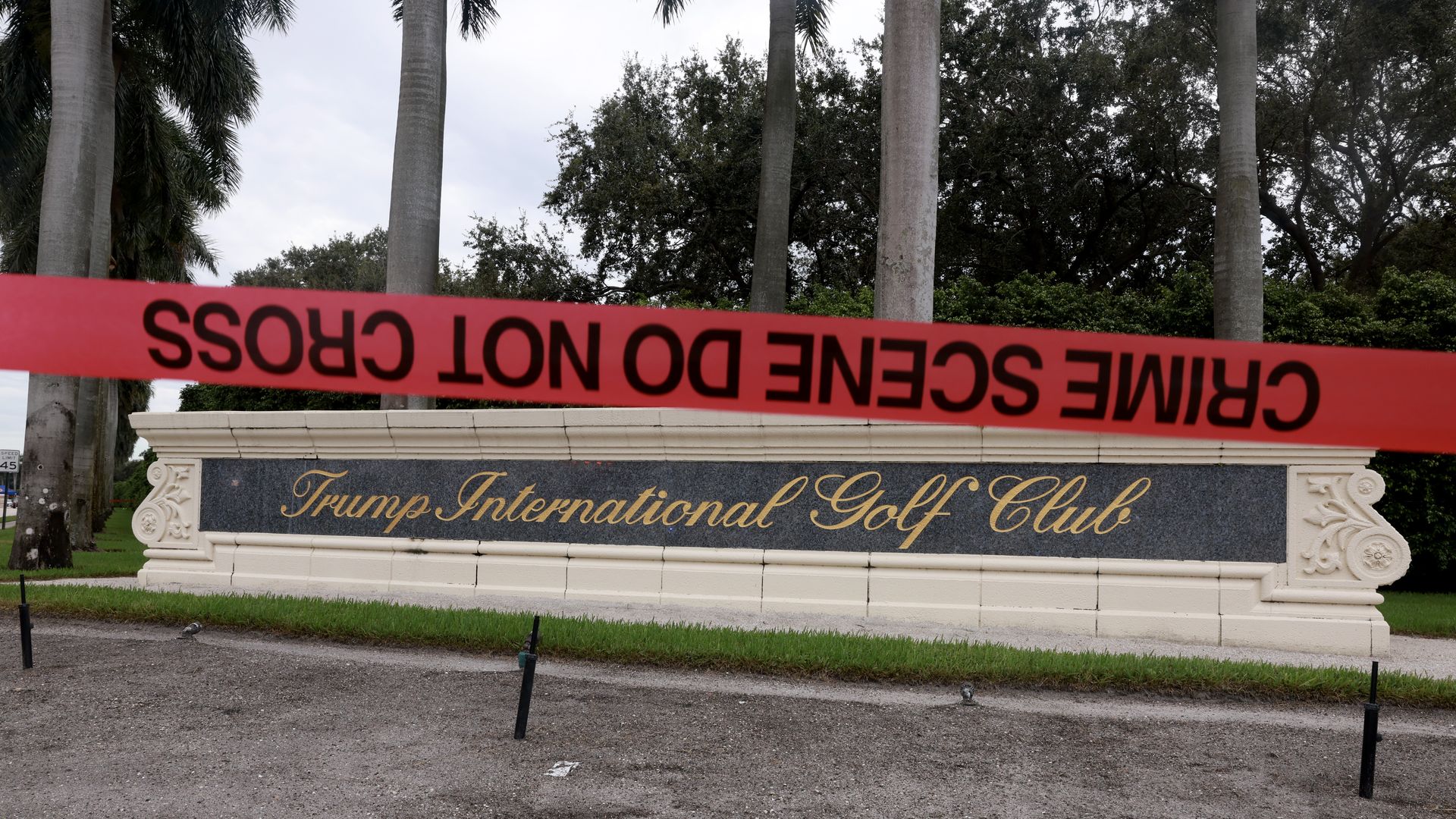 Red crime scene tape is visible in front of a Trump International Golf Club entrance sign