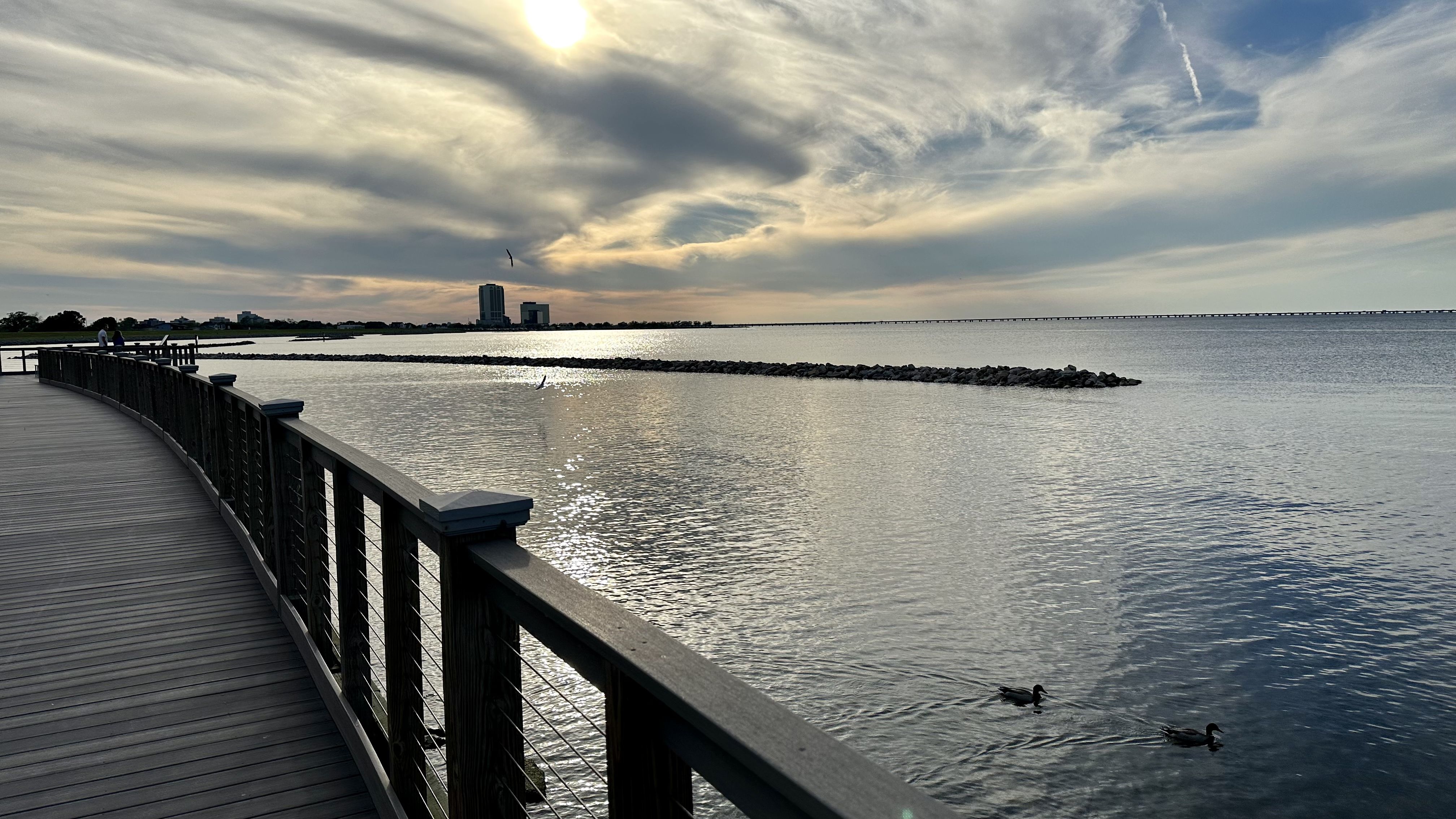 Photo shows the boardwalk and one of the new rock jetties as sunset on Lake Pontchartrain.