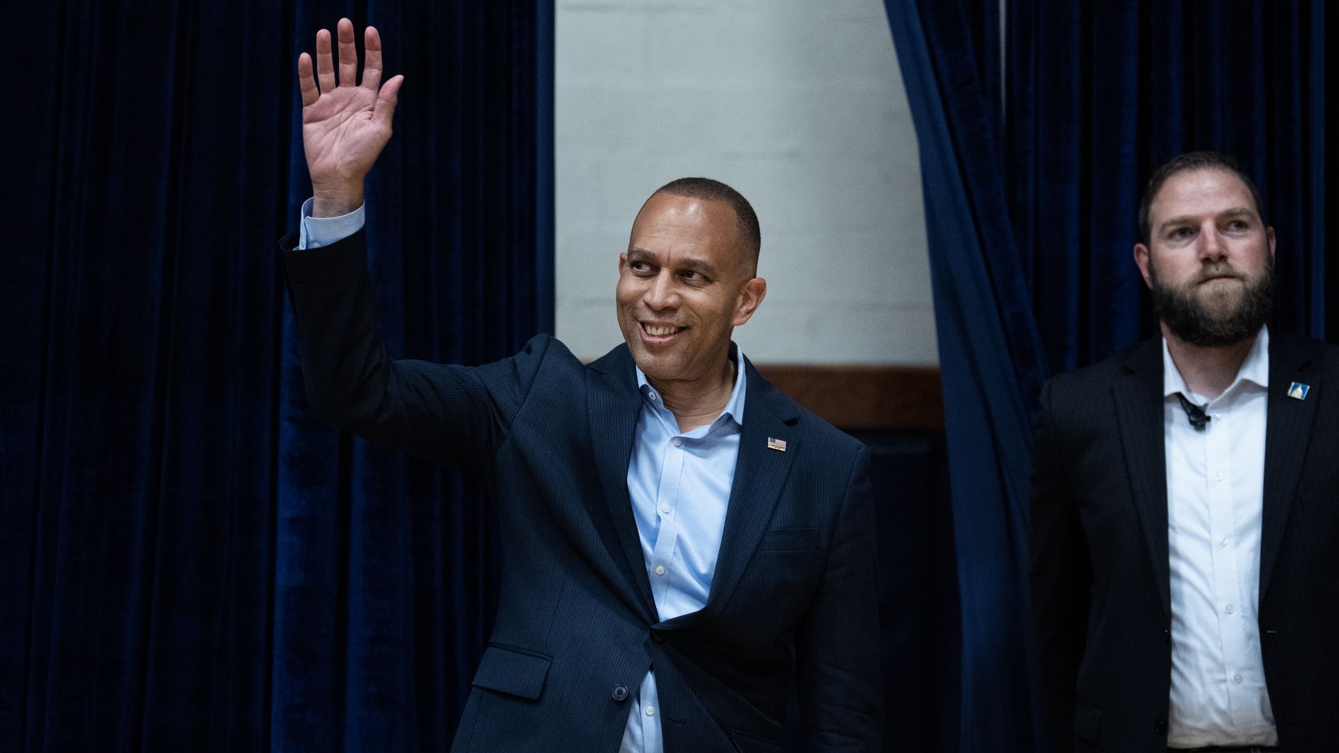Rep. Hakeem Jeffries, wearing a blue suit and waving his hand.
