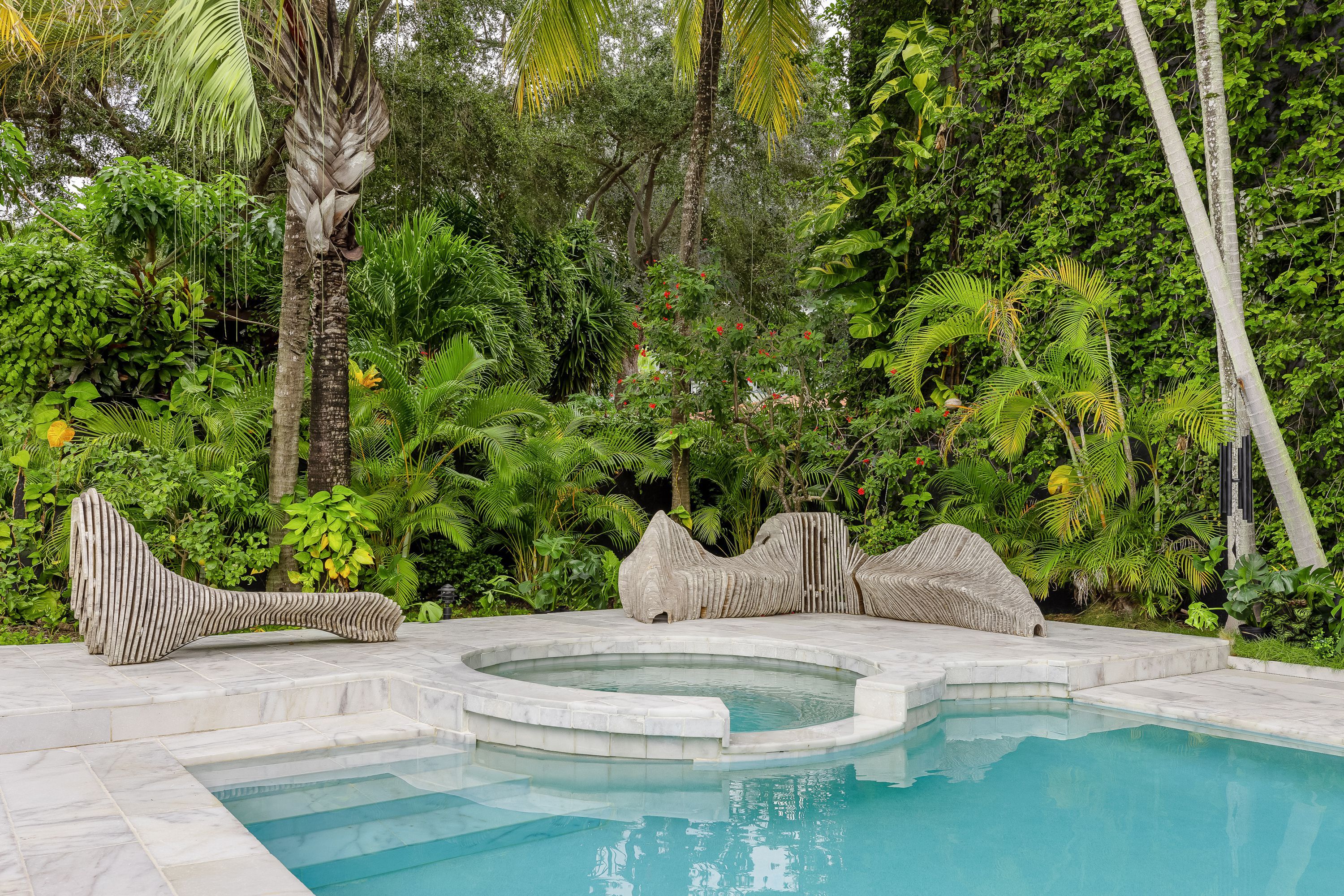 Backyard pool surrounded by tropical plants.