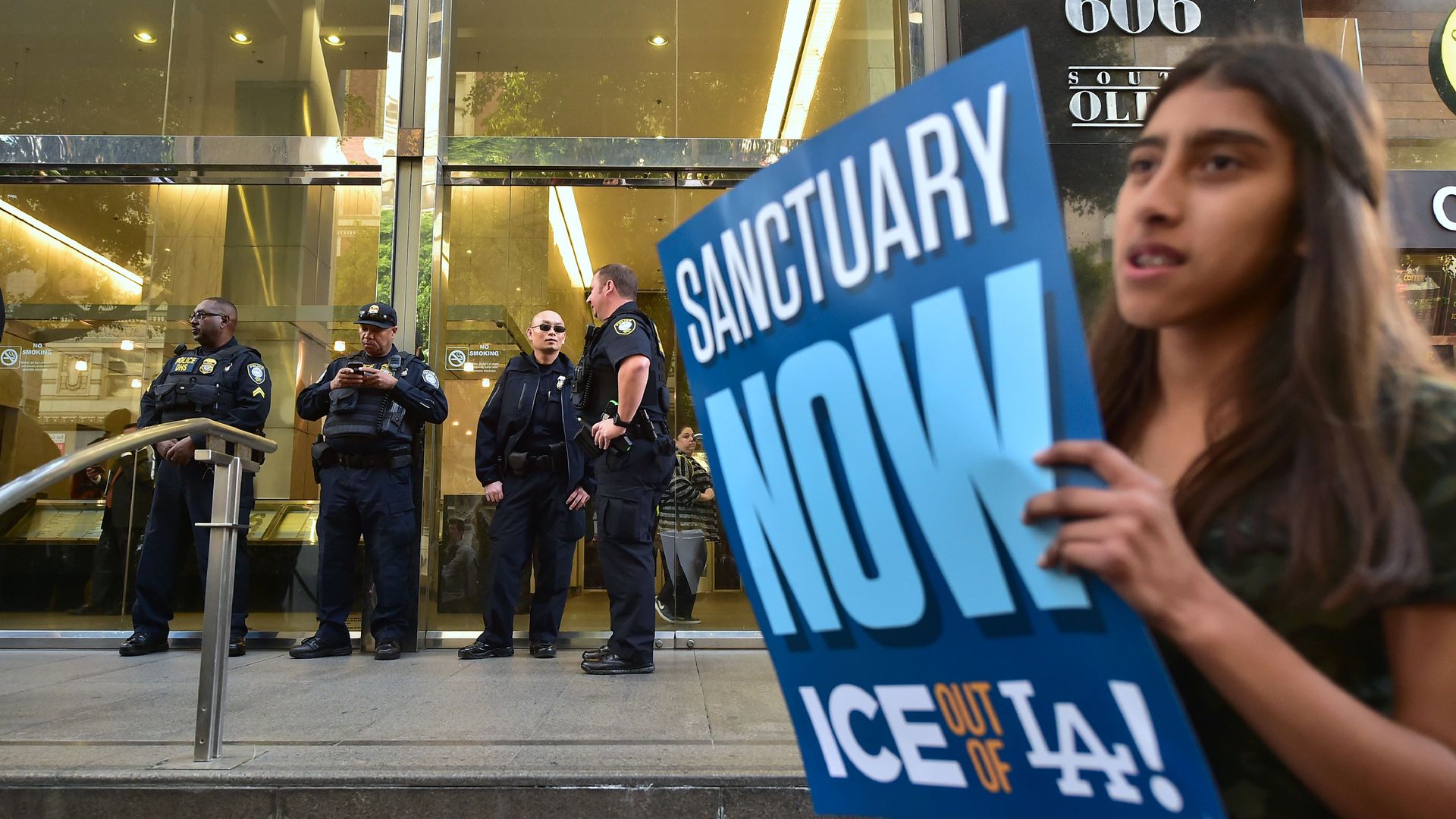 Department of Homeland Security police officers stand guard in front of a Los Angeles Immigration Court building during a rally against an arrest by ICE agents.