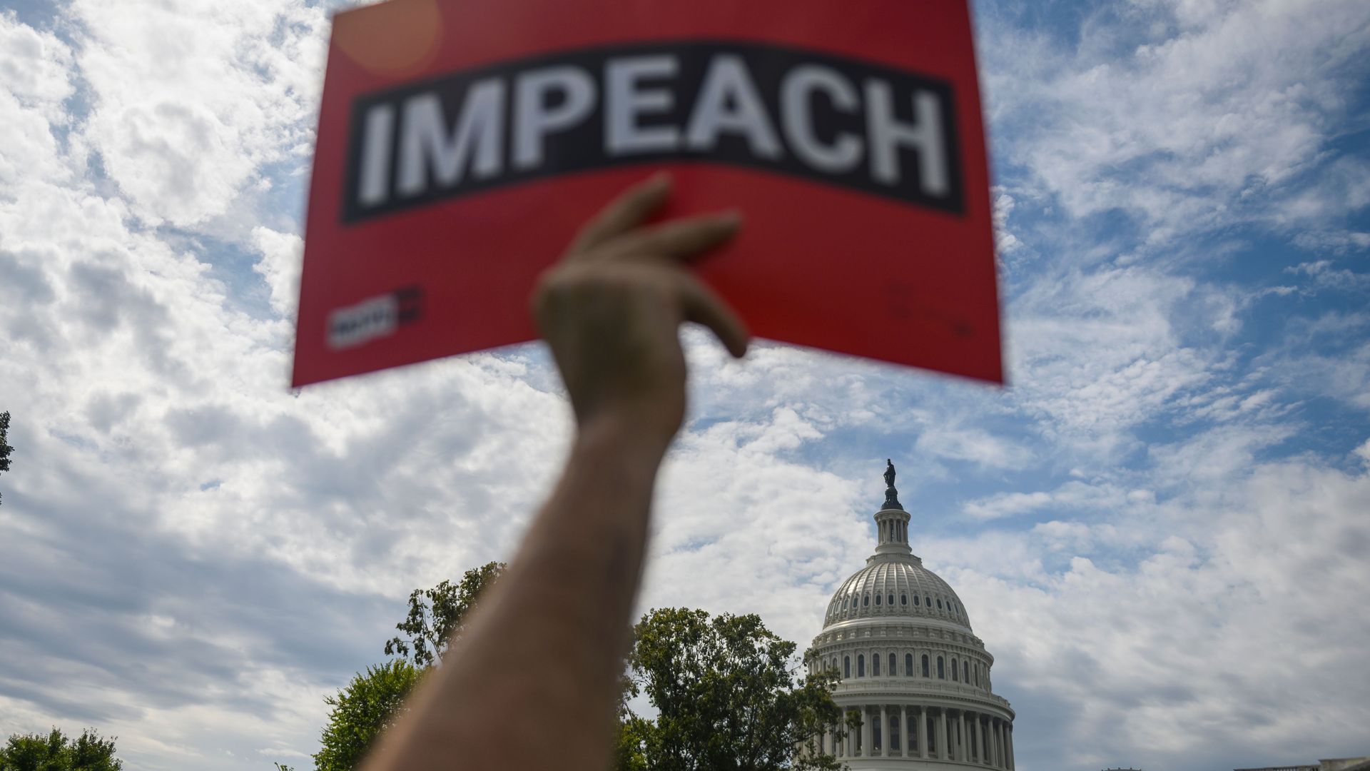 A protester holds up a sign reading "impeach" outside the US Capitol building