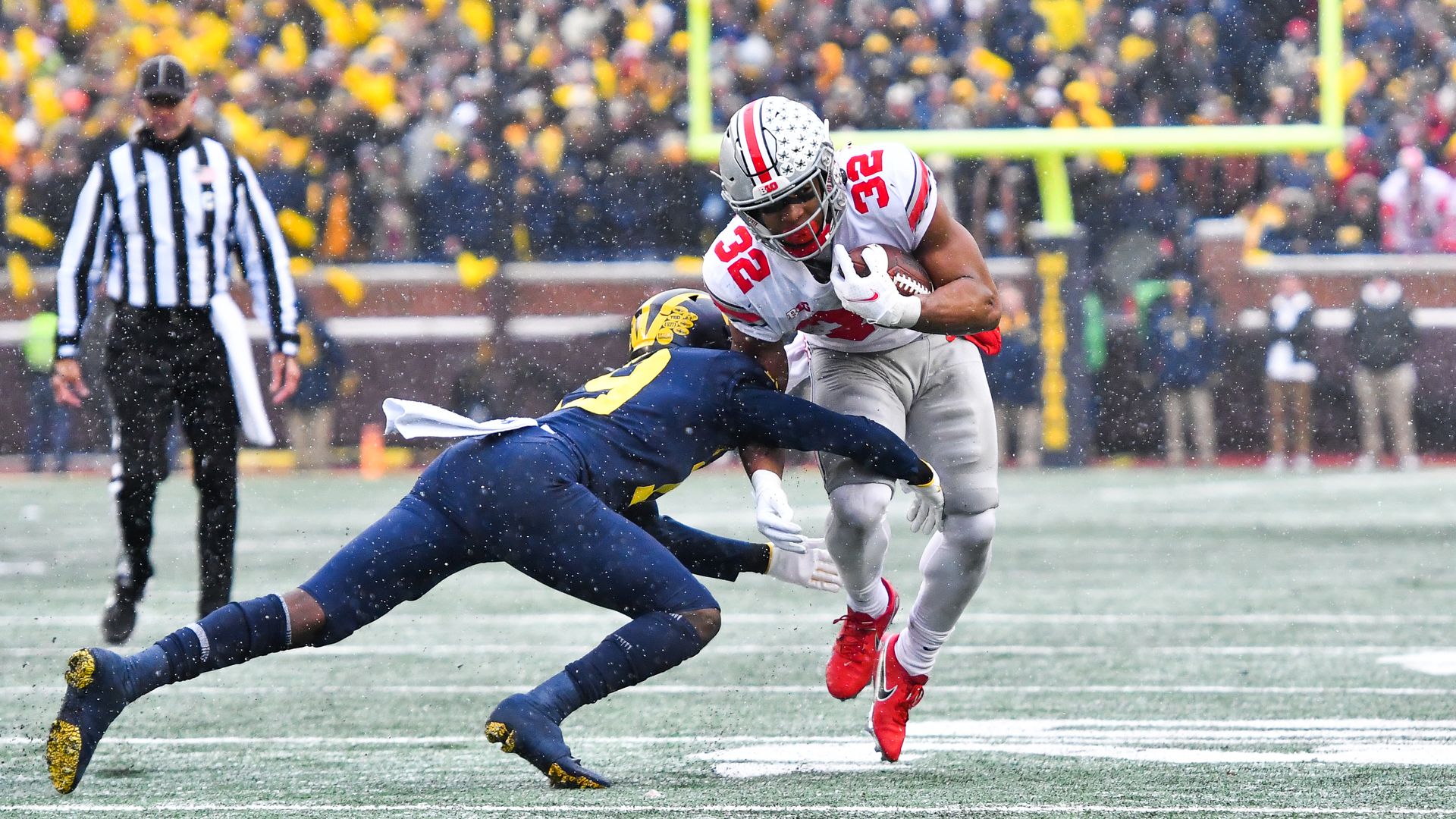 An Ohio State football player tries to run around a Michigan defender, who lays out to tackle him.