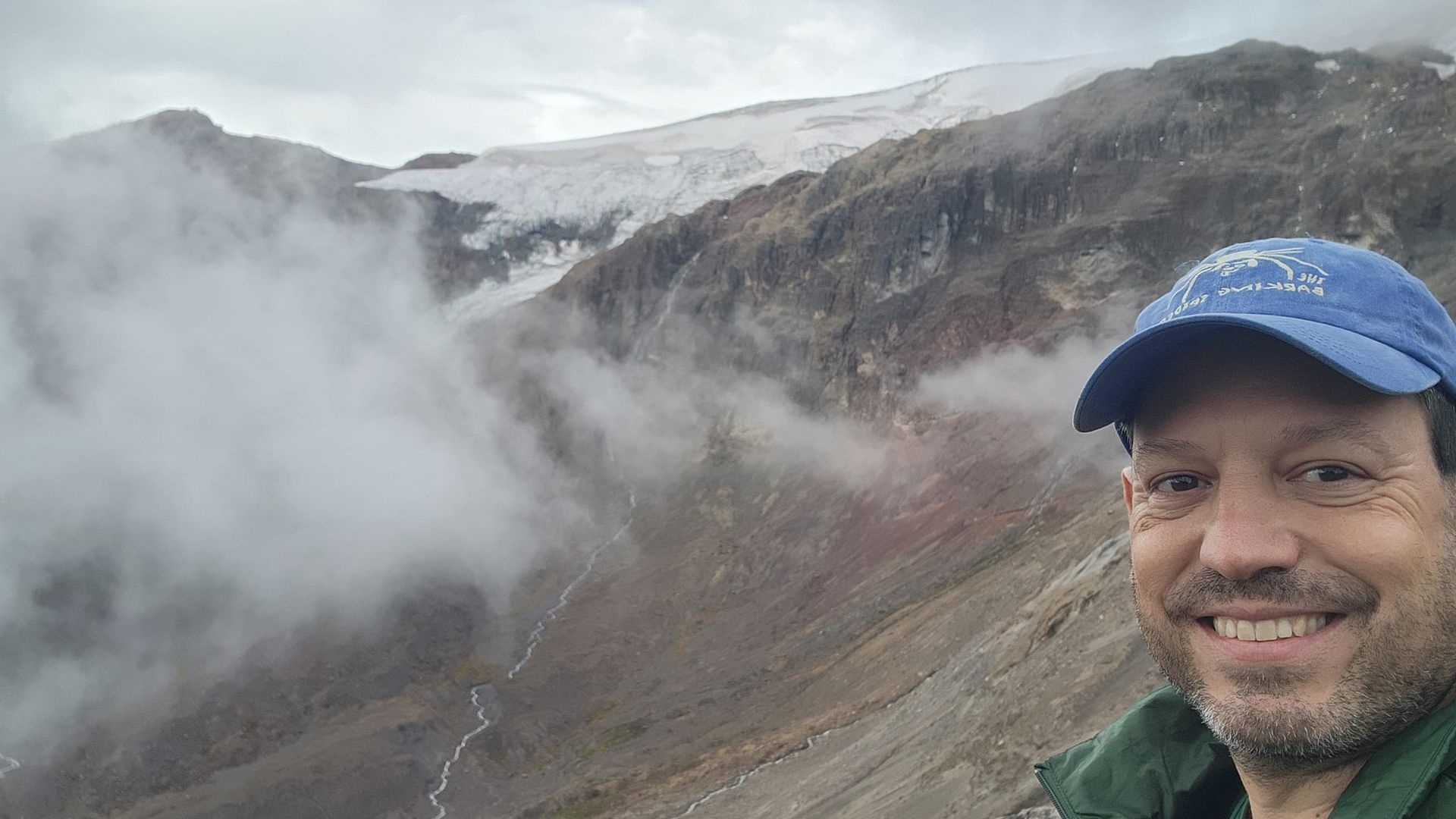 Virginia state senator Scott Surovell wearing a blue baseball cap in front of peaks