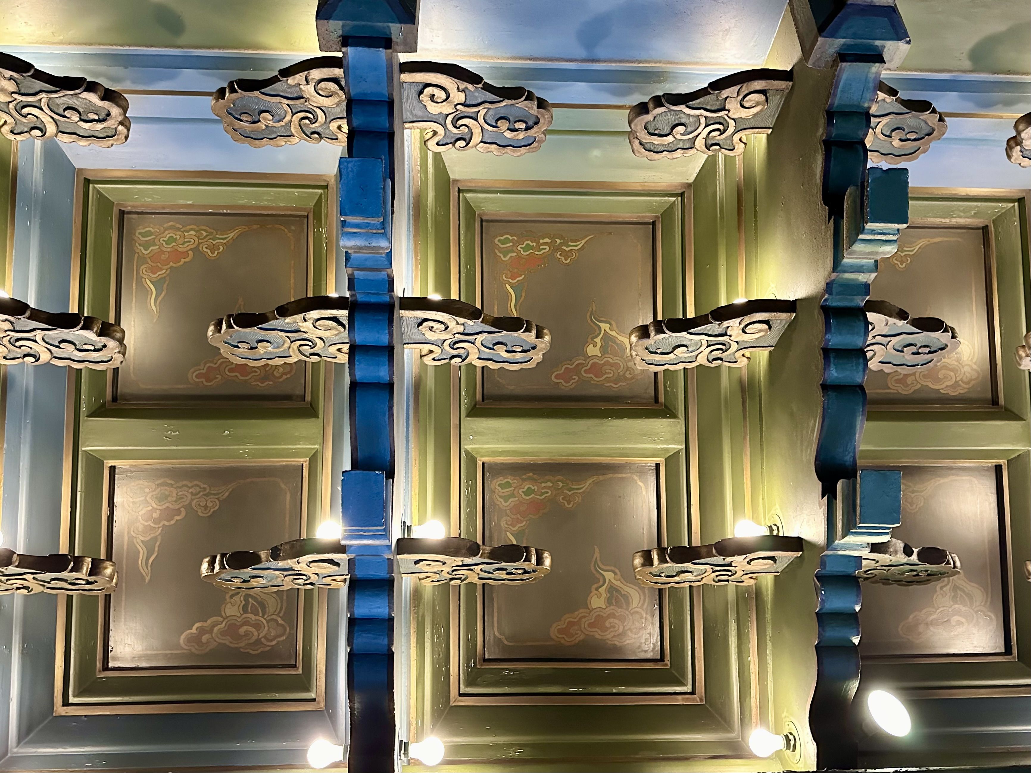 A view of coffered ceiling and decorative elements, with lighting.