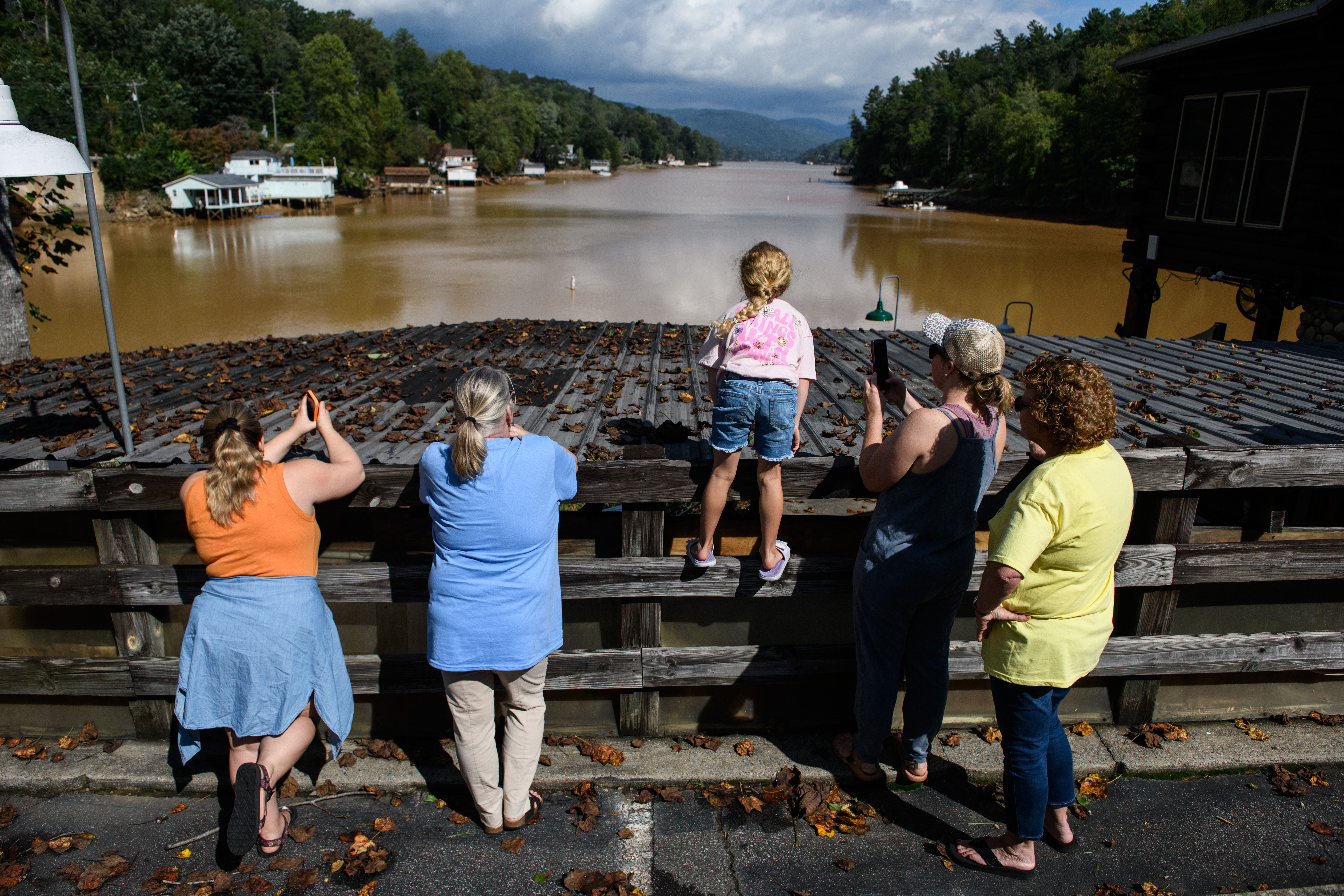 a family looks out over the Broad River in Lake Lure after Tropical Storm Helene.