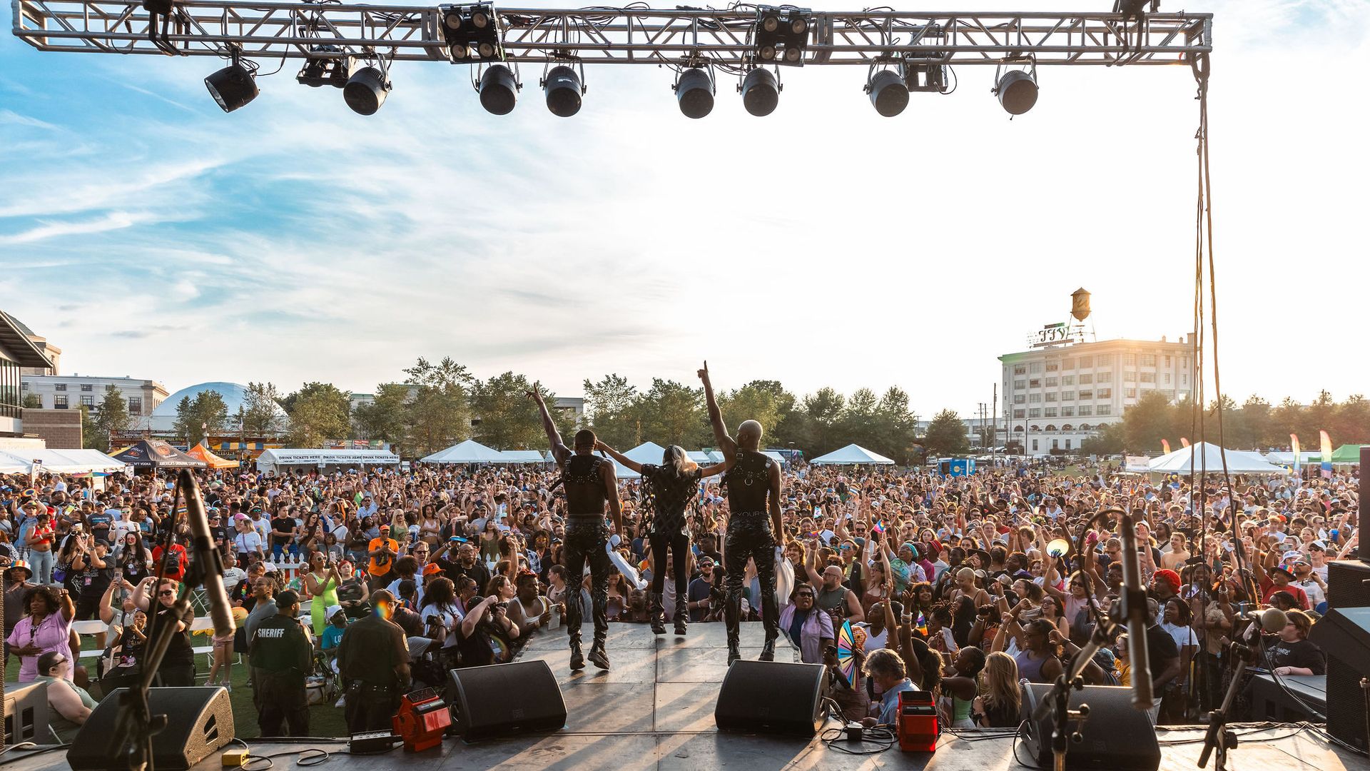 three people on a stage looking out onto a packed crowd