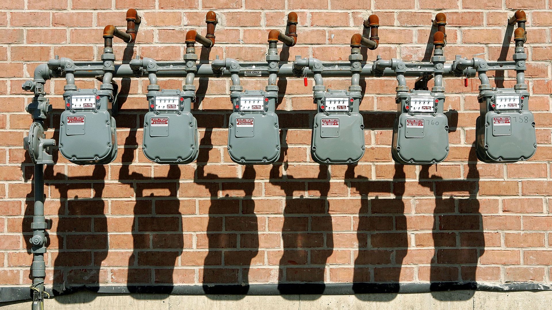 natural gas meters against a brick wall