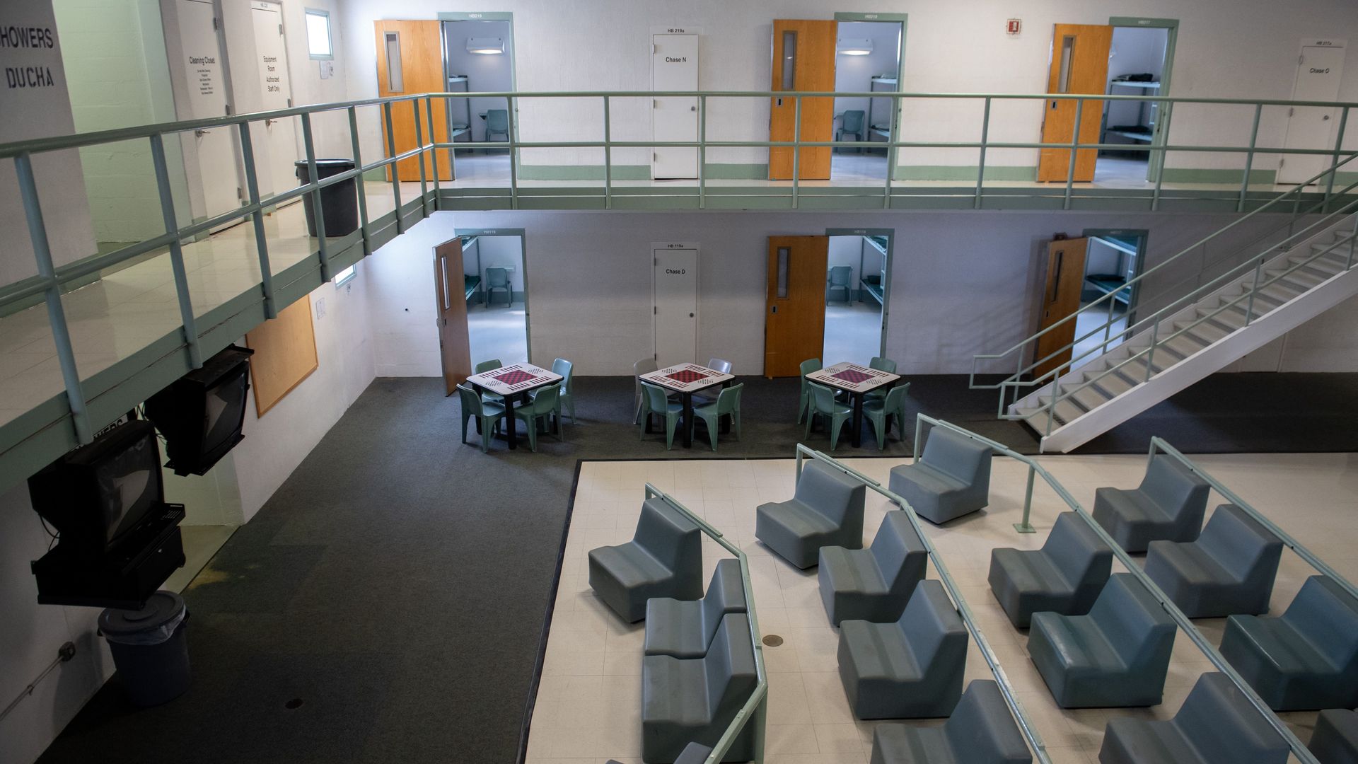 This image shows a birds eye view of a large room with rows of plastic green chairs and a catwalk around the top of the wall.