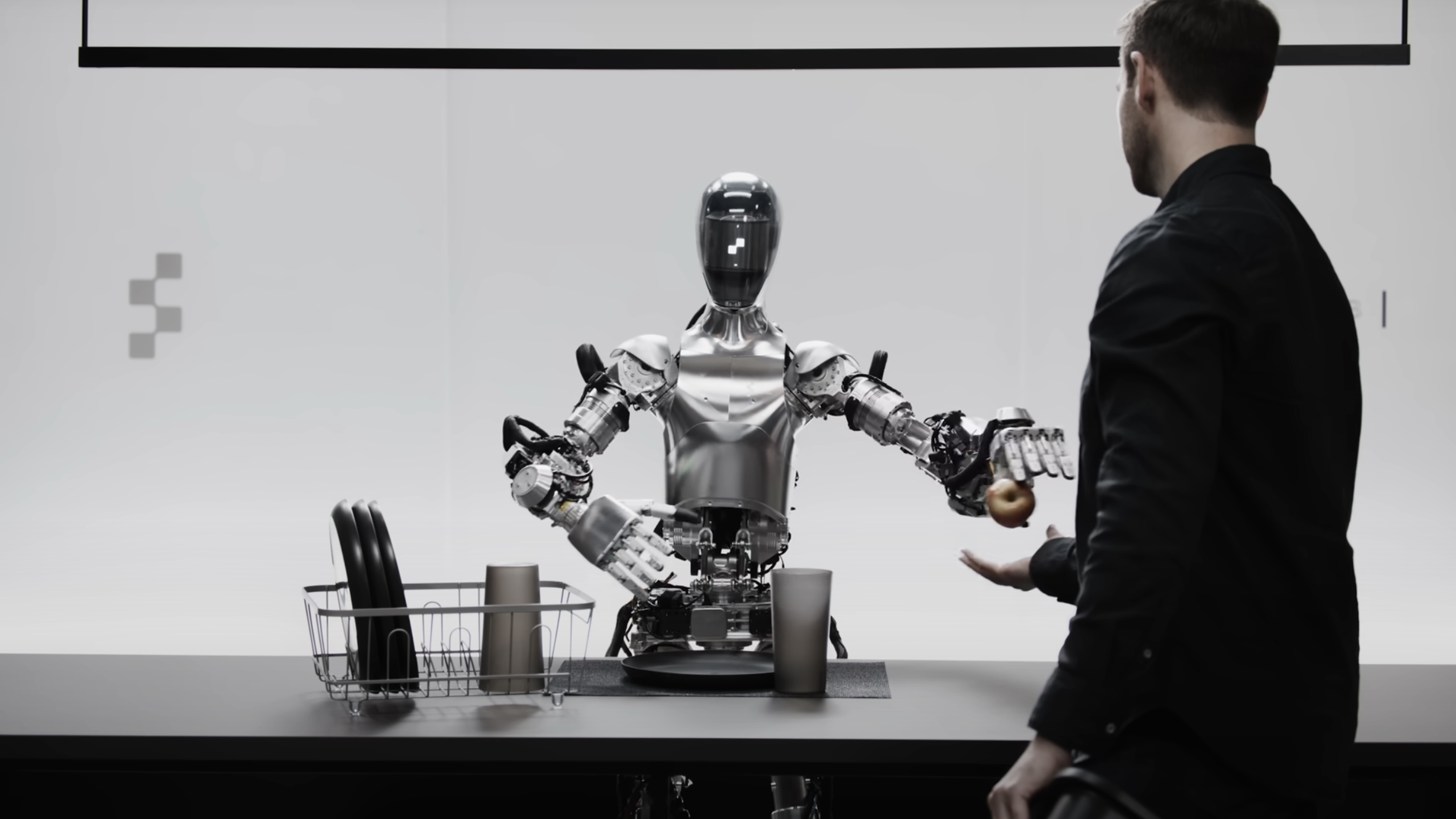 A Figure robot handing a person an apple.