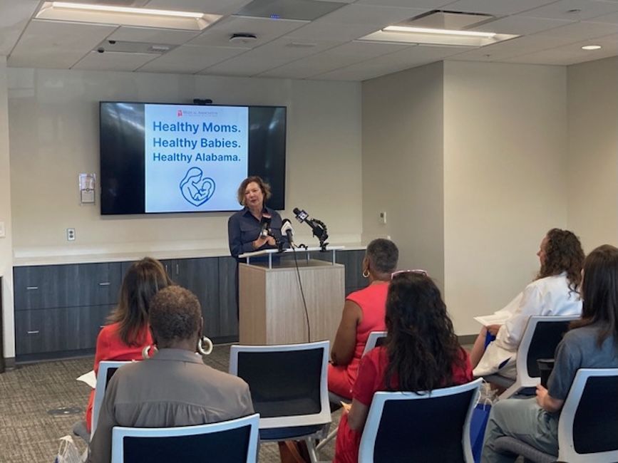 Rep. Marilyn Lands speaks to a group of women in front of a screen that reads: Healthy Moms. Healthy Babies. Healthy Alabama