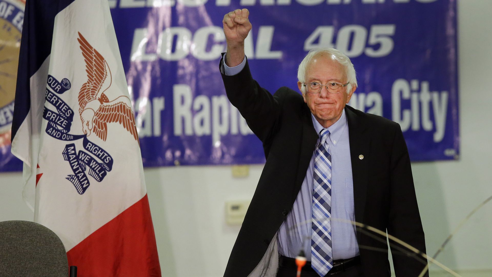 Bernie Sanders raises a fist at a crowd.