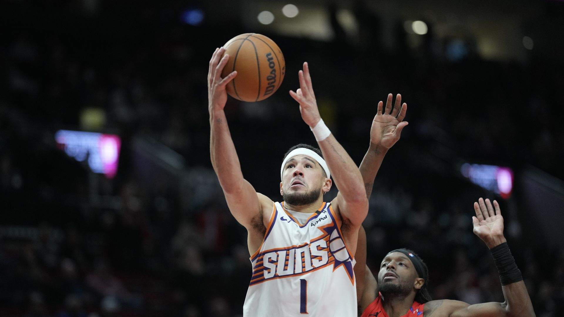 Devin Booker puts up a shot over a defender.