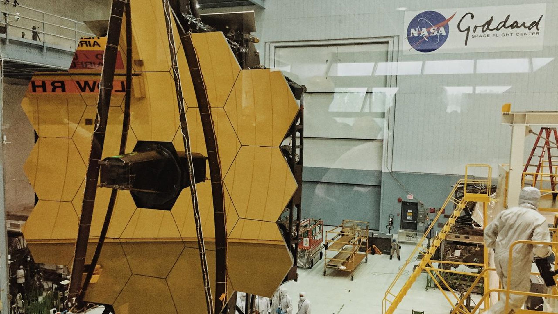 The James Webb Space Telescope in a clean room on Earth with its gold-plated primary mirror unfurled.