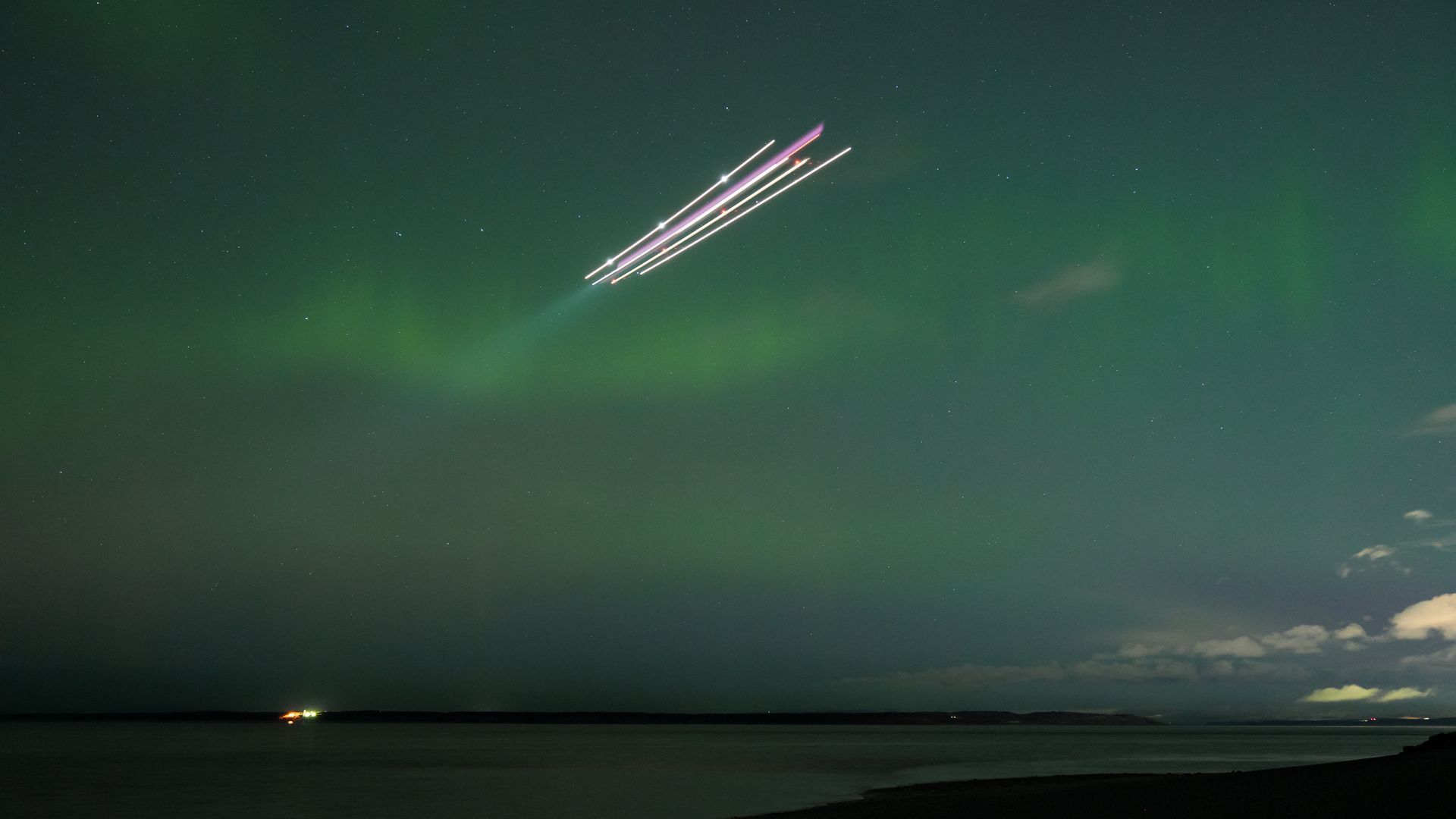 Green and purple aurora borealis streaks across the night sky above city lights in Anchorage, Alaska, on Oct. 18, 2025.