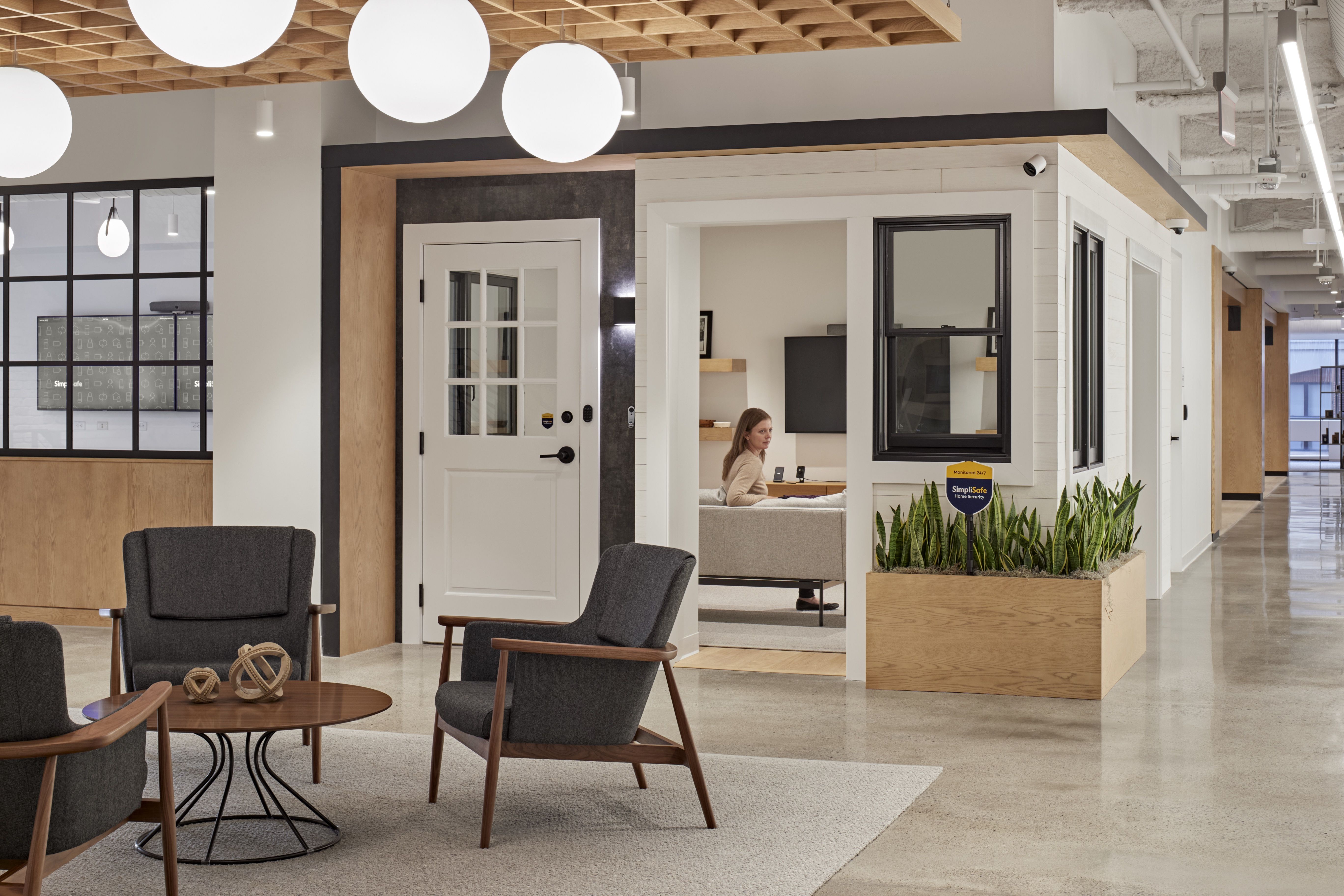 An employee sits on a couch inside the model living room at SimpliSafe's Boston HQ. It's a "tiny home" where workers can see what the products look like once installed.